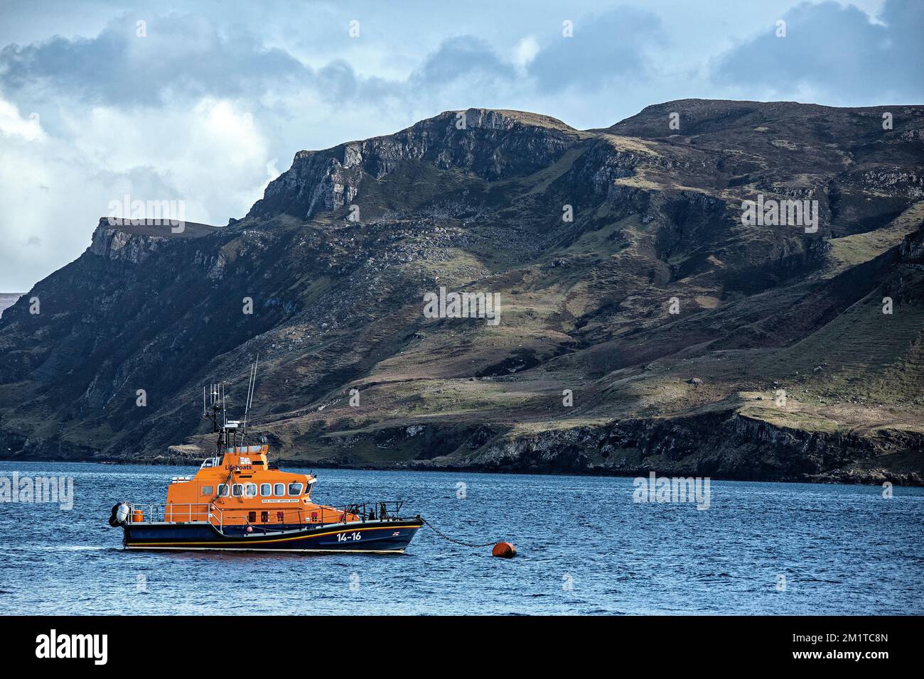 Le Portree Life Boat à l'ancre dans le port avec les imposantes falaises derrière, sur l'île de Skye. Banque D'Images