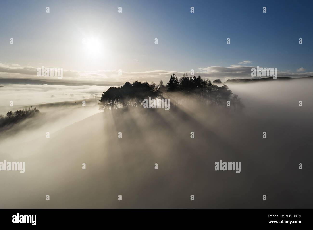 Le soleil illuminant l'ancien arbre couvert Tumulus de Kirkcarrion crée quelques belles rayons crépusculaires comme brouillard Swirls autour du paysage, au nord Banque D'Images