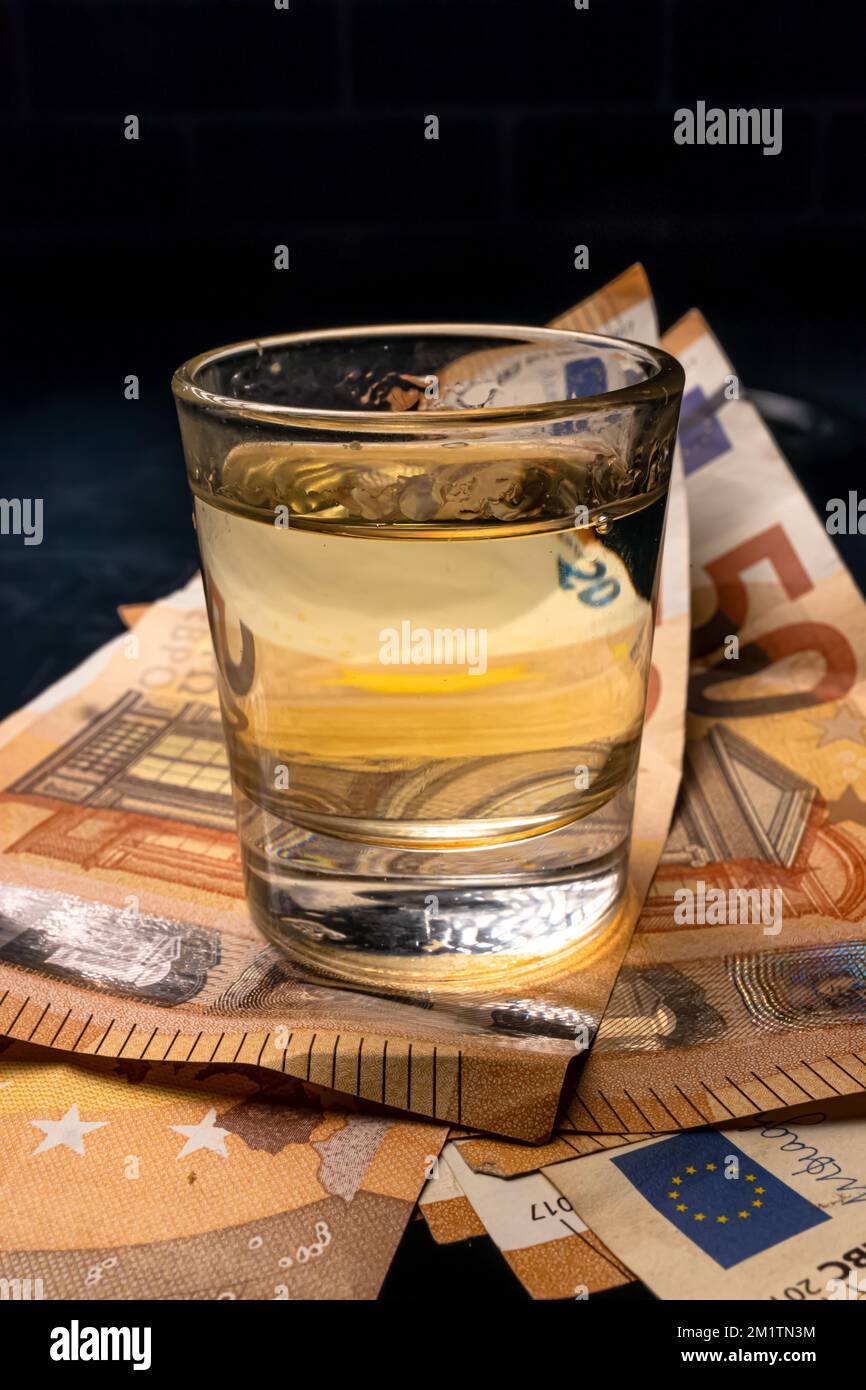 Un cliché vertical d'un verre de tequila sur des billets en euros Banque D'Images