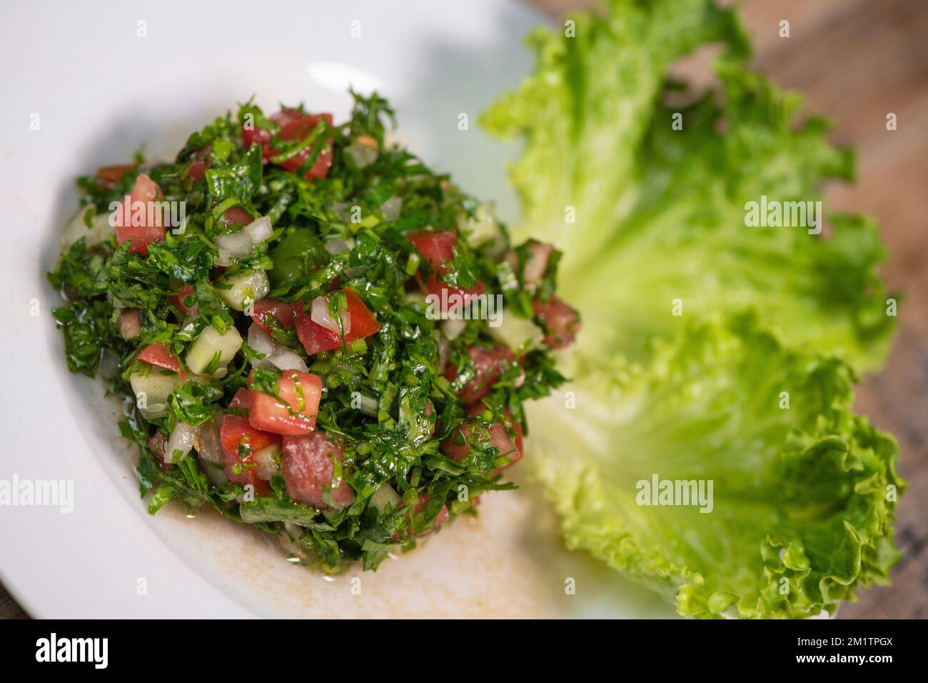 Plat de salade de tabouleh du Moyen-Orient avec laitue sur fond blanc. Banque D'Images