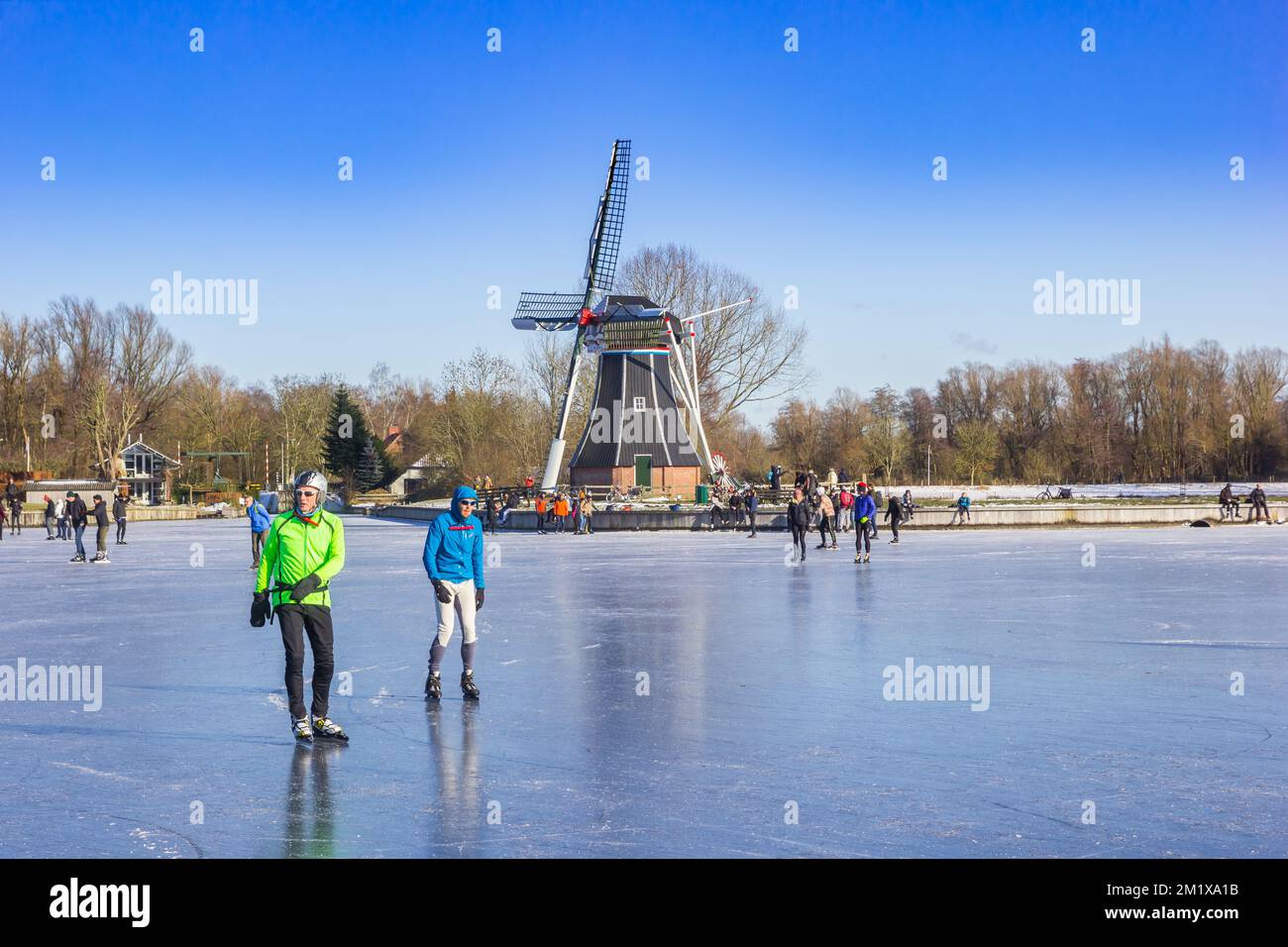 Patineurs devant le moulin à vent au lac gelé de Groningen, pays-Bas Banque D'Images