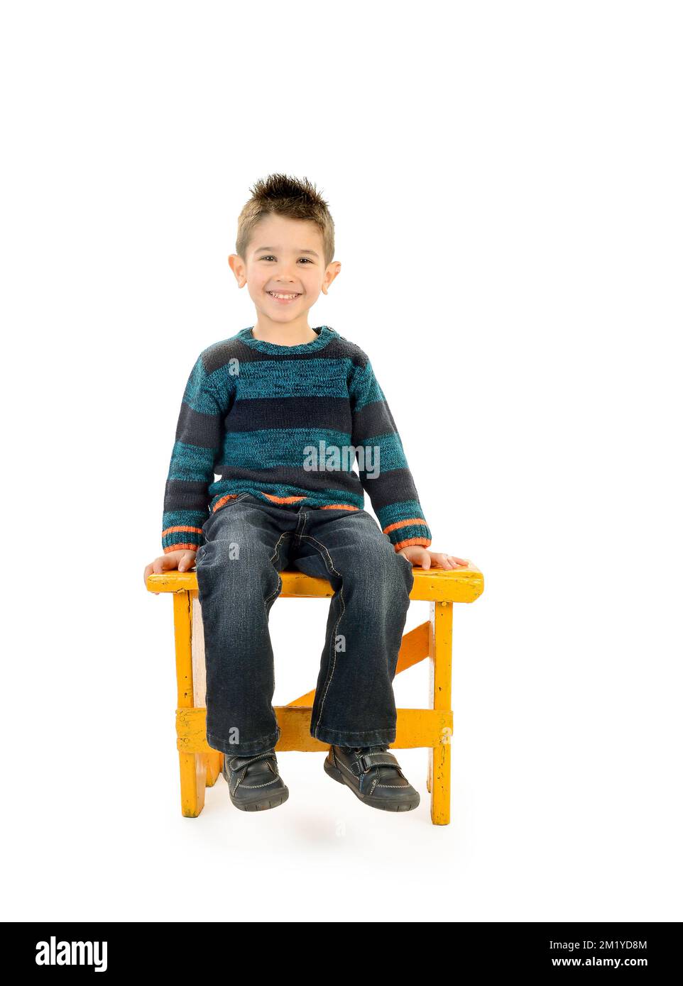Enfant isolé souriant assis sur un banc jaune. Banque D'Images