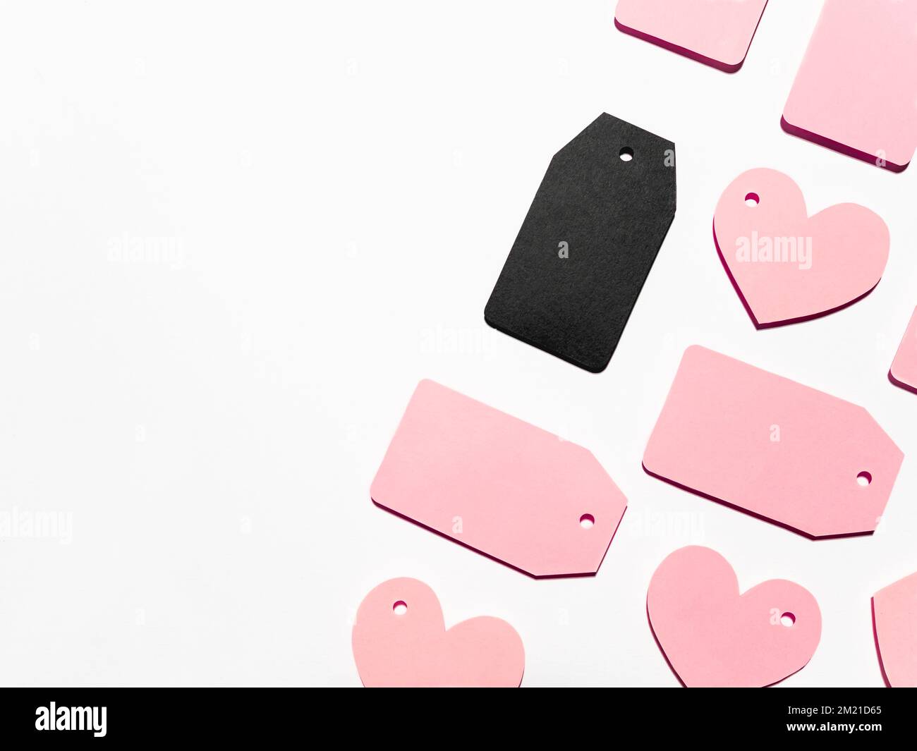 Vue de dessus sur le motif de nombreuses étiquettes de vêtements roses et noires sur fond blanc. Étiquettes glamour avec espace de copie. Symbole de la vente et du sho du vendredi noir Banque D'Images
