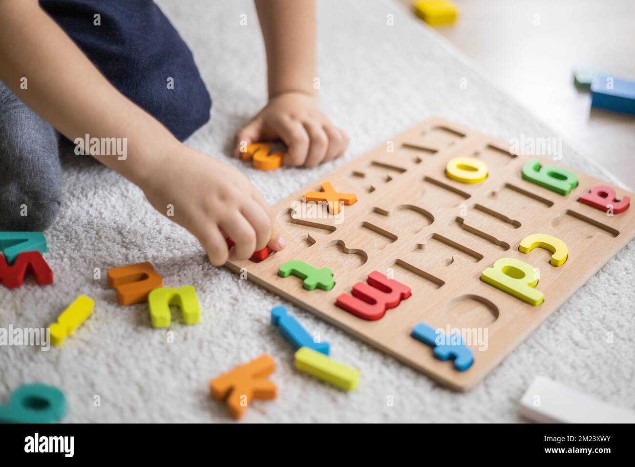 Enfant de sexe masculin jouant avec des lettres de l'alphabet écologique en  bois sur le plateau de table vue du jeu intellectuel Photo Stock - Alamy