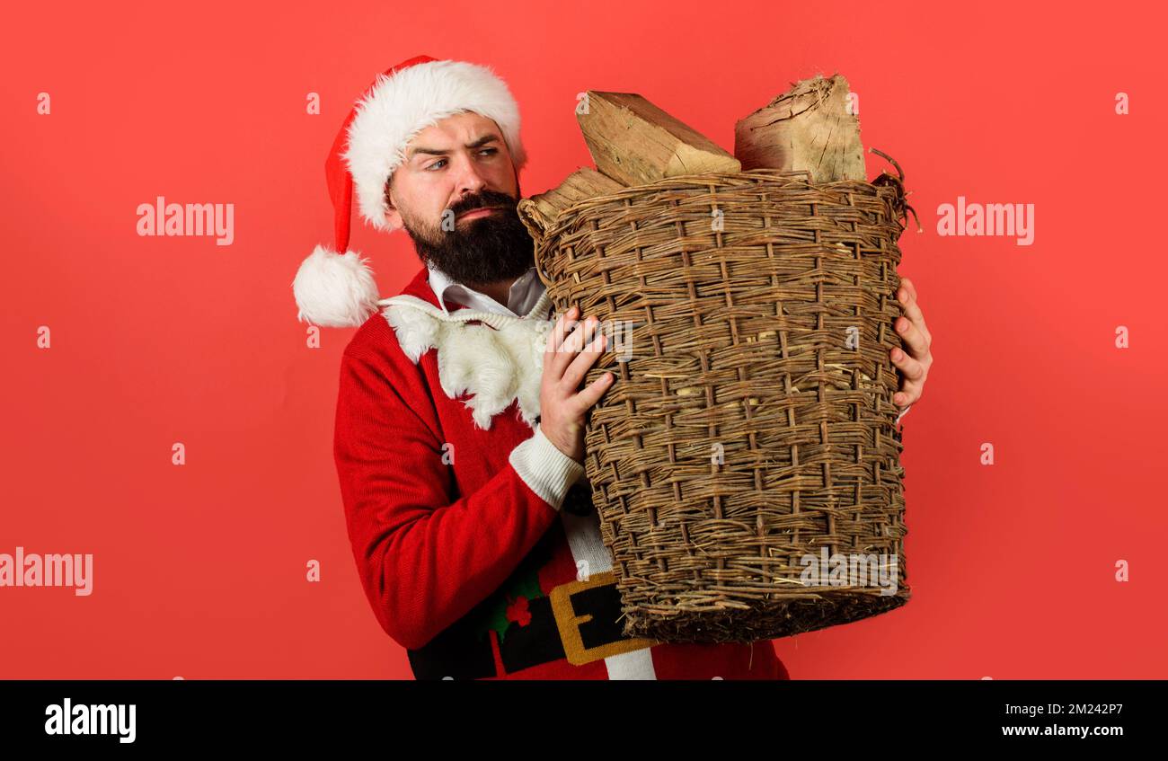 Joyeux Noël. Santa Claus avec panier en osier de bois de chauffage haché pour la cheminée. Vacances Banque D'Images