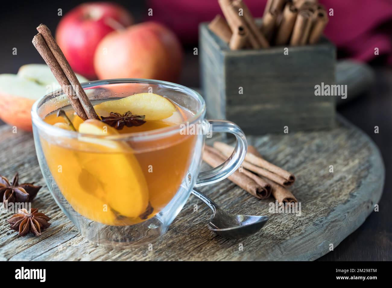 Une tasse de thé remplie de cidre de pomme chaud avec tous les ingrédients à l'arrière. Banque D'Images