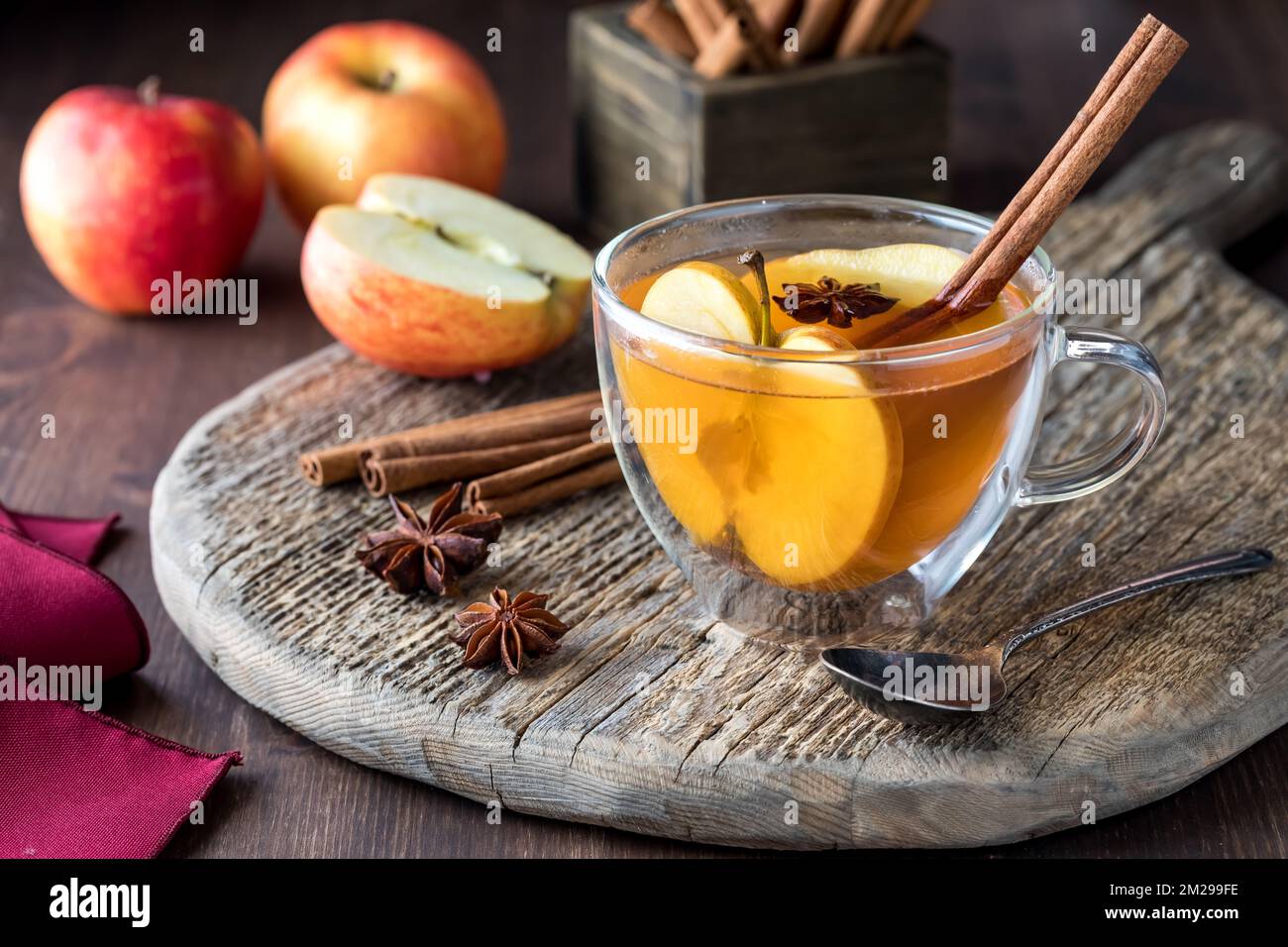 Cidre de pomme chaud avec tous les ingrédients à côté, sur une planche de bois rustique. Banque D'Images