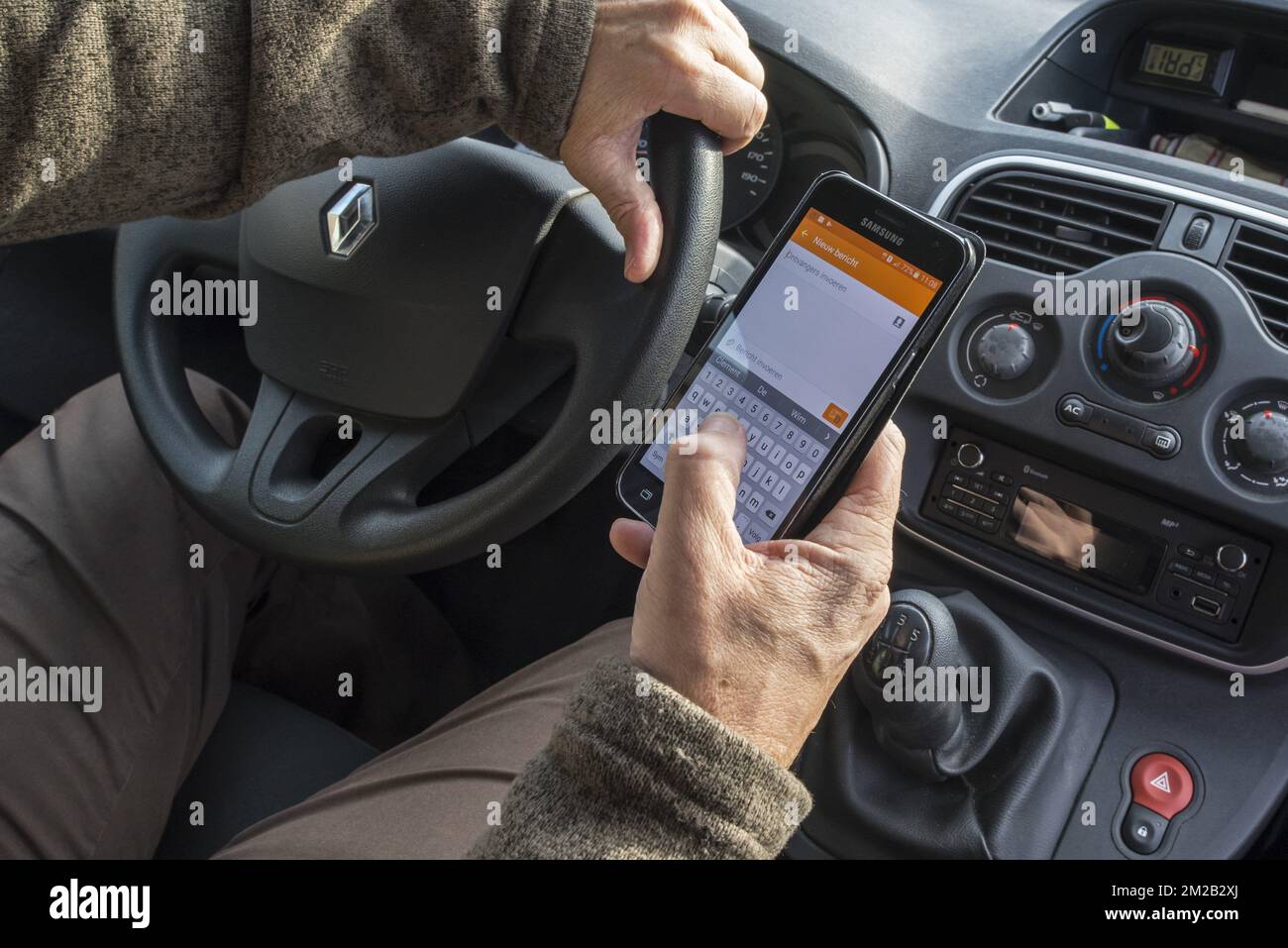 Homme irresponsable au volant envoyant un message par SMS / SMS sur smartphone / téléphone portable en voiture sur route | Homme derrière volant en train de transmette un message par smartphone / téléphone mobile en roulant en mobilier 17/11/2017 Banque D'Images