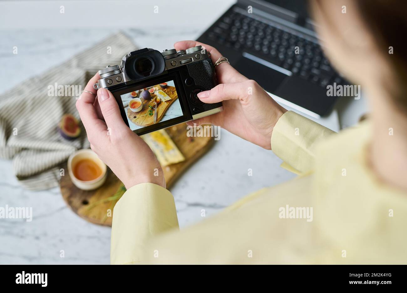 Gros plan d'une femme qui prend des photos de nourriture sur une planche de bois à l'aide de son appareil photo professionnel Banque D'Images
