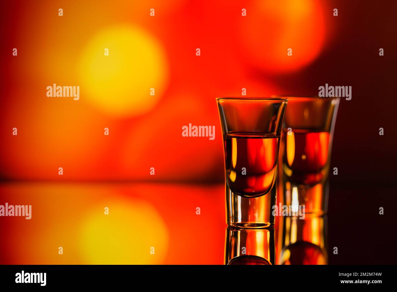Deux verres de whisky ou de bourbon sur fond de bokeh rouge. Concept d'humeur whiskey Banque D'Images