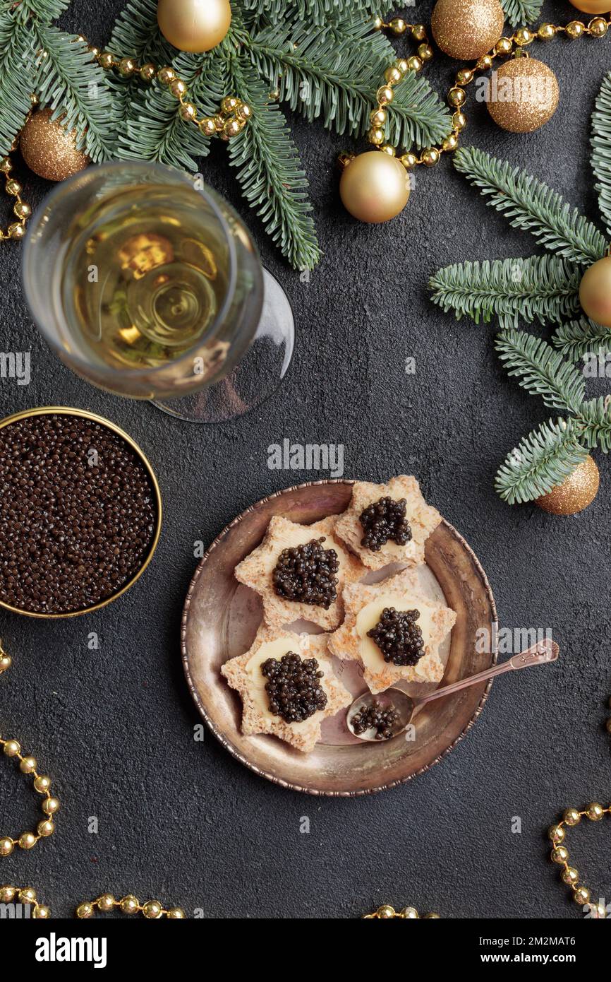 Caviar noir hors-d'œuvre étoiles sur une table noire décorée de noël vertical Banque D'Images