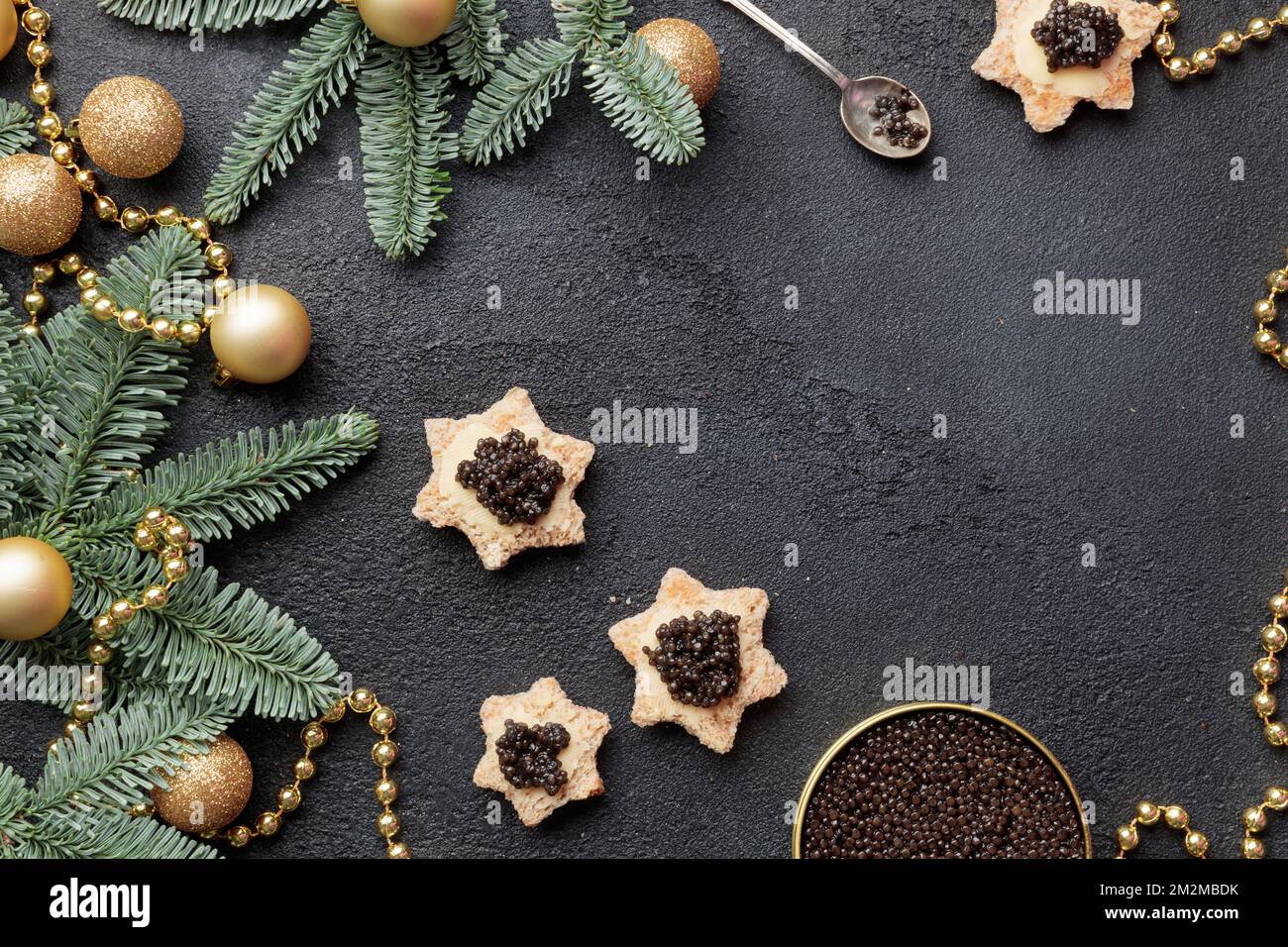 Caviar noir hors-d'œuvre étoiles sur une table noire décorée de noël Copyspace horizontal Banque D'Images