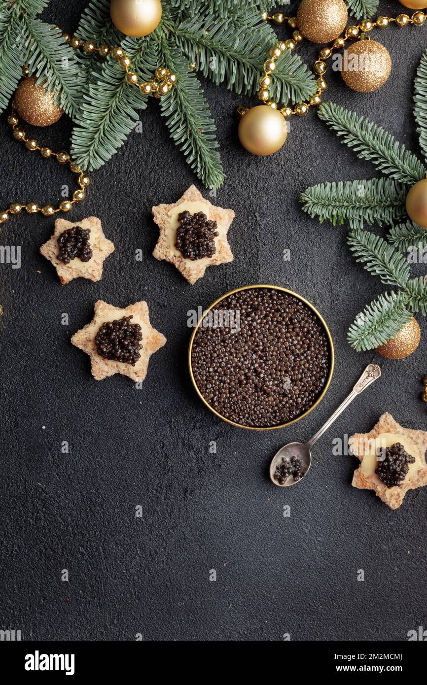 Caviar noir hors-d'œuvre étoiles sur une table noire décorée de noël Copyspace vertical Banque D'Images