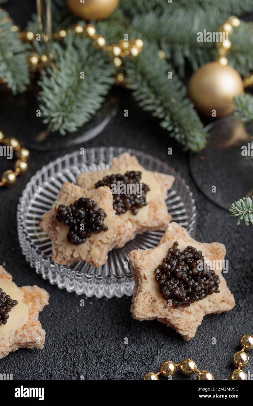 Caviar noir hors-d'œuvre étoiles sur une table noire décorée de noël vertical Banque D'Images
