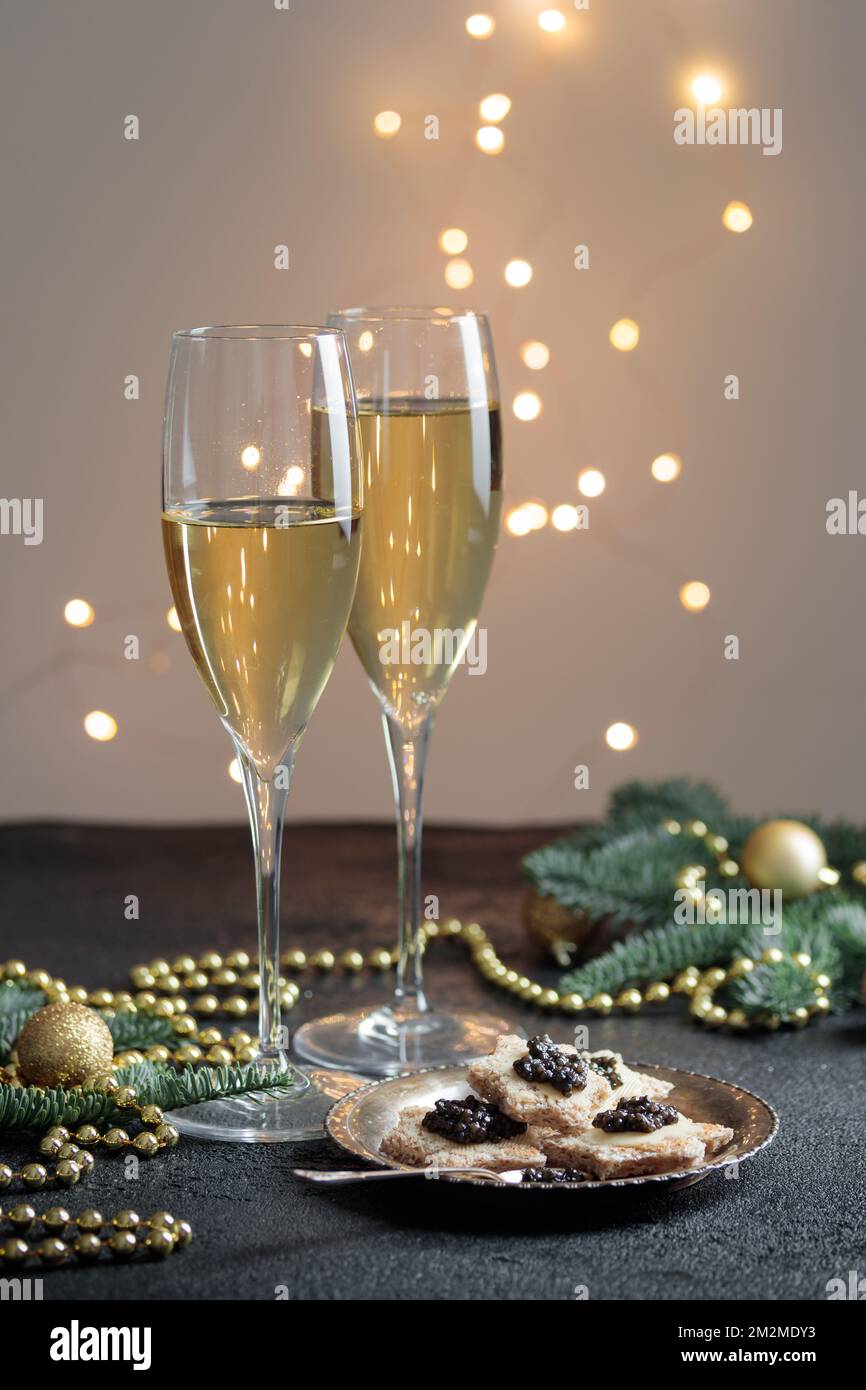 Caviar noir hors-d'œuvre étoiles sur une table noire décorée de noël avec champagne et bokeh vertical Banque D'Images