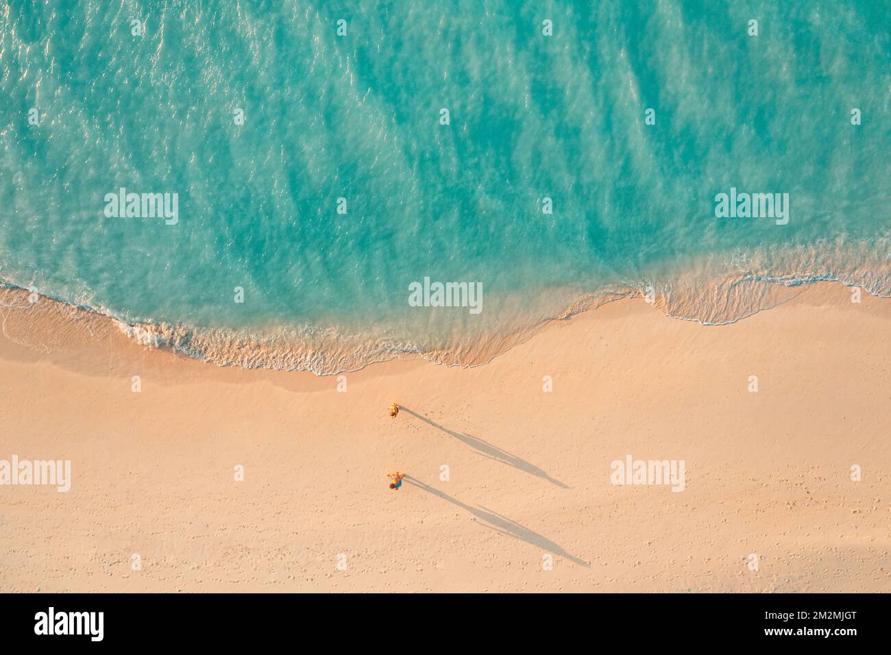 Vue aérienne romantique de couple marchant sur le coucher de soleil lumière plage longues ombres idyllique été vacances aventure humeur. Activités de loisirs en extérieur top drone Banque D'Images