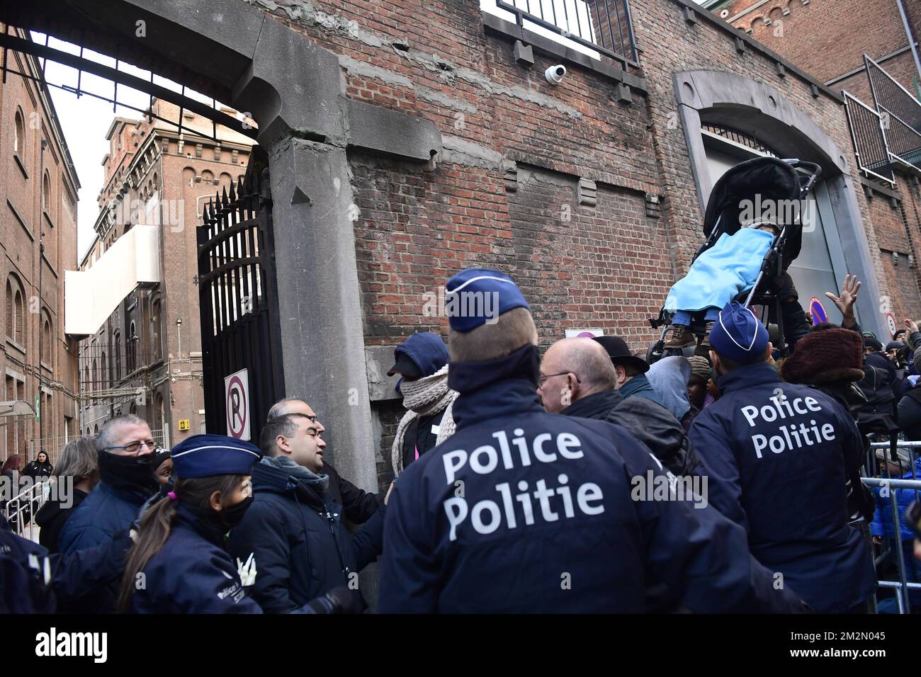 La police regarde les gens dans la foule soulever un buggy avec un enfant à l'intérieur, tandis que les gens font la queue dehors pour entrer à l'entrée arrière du nouveau centre d'enregistrement pour les demandeurs d'asile au 'petit Château - Klein Kasteeltje' à Bruxelles, lundi 10 décembre 2018. En raison d'un manque d'espace, les Services étrangers (DVZ Dienst Vreemdelingenzaken - ODE Office des Etrangers) l'enregistrement y a déménagé des bureaux près de Maximiliaanpark - Parc Maximilien. BELGA PHOTO LAURIE DIEFFEMBACQ Banque D'Images