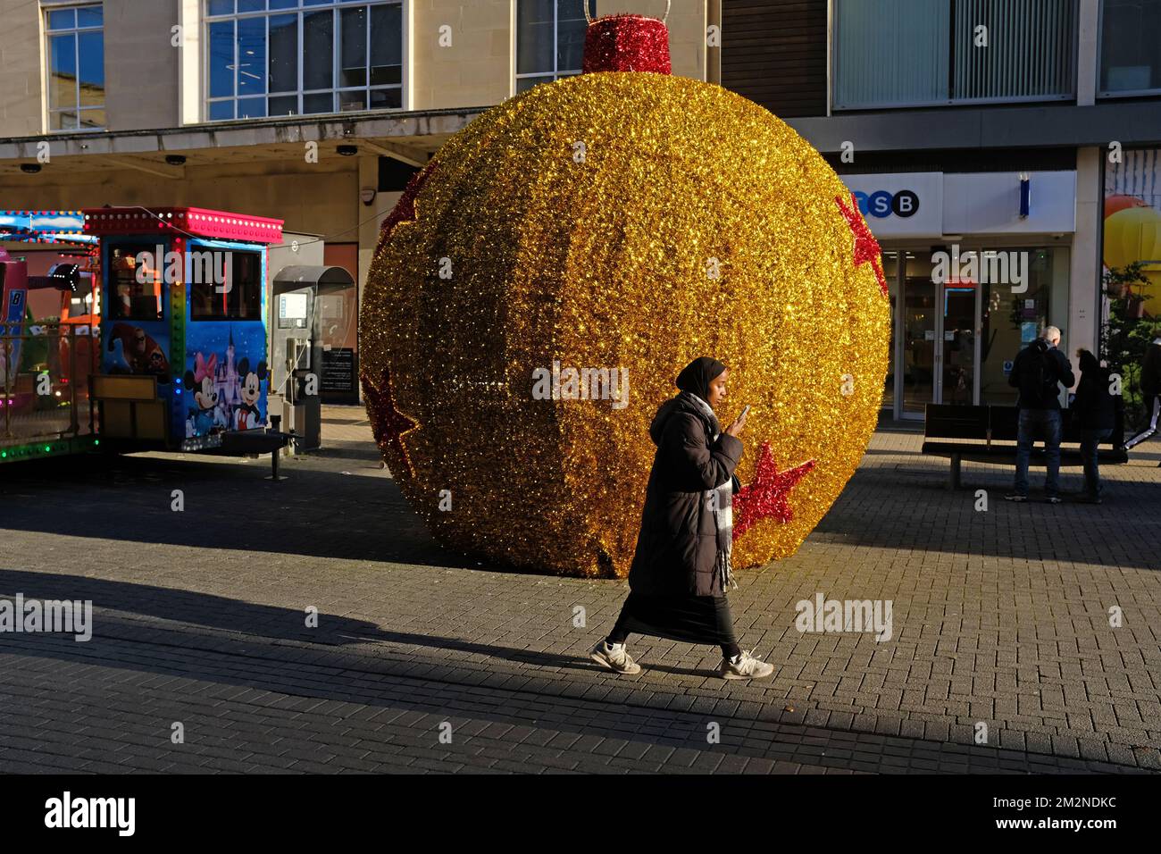 Une jeune femme musulmane marchant devant une décoration de Noël dans un centre commercial de Britolshopping. Banque D'Images