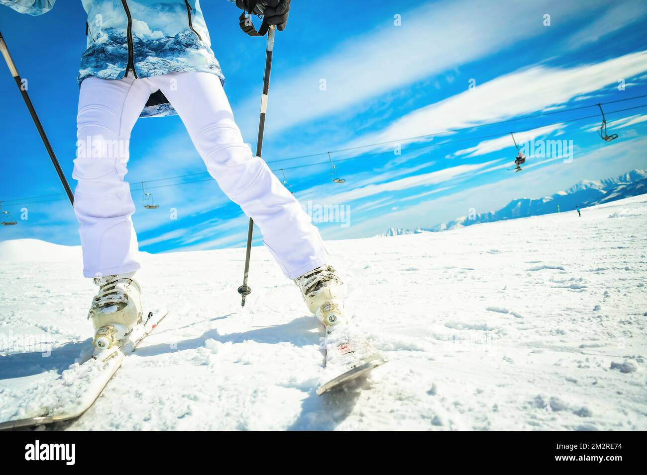 Femme skieuse en gros plan vue de fond lumineuse sur les chaussures de ski et les skis tout en s'arrête sur la sculpture en mouvement rapide Banque D'Images