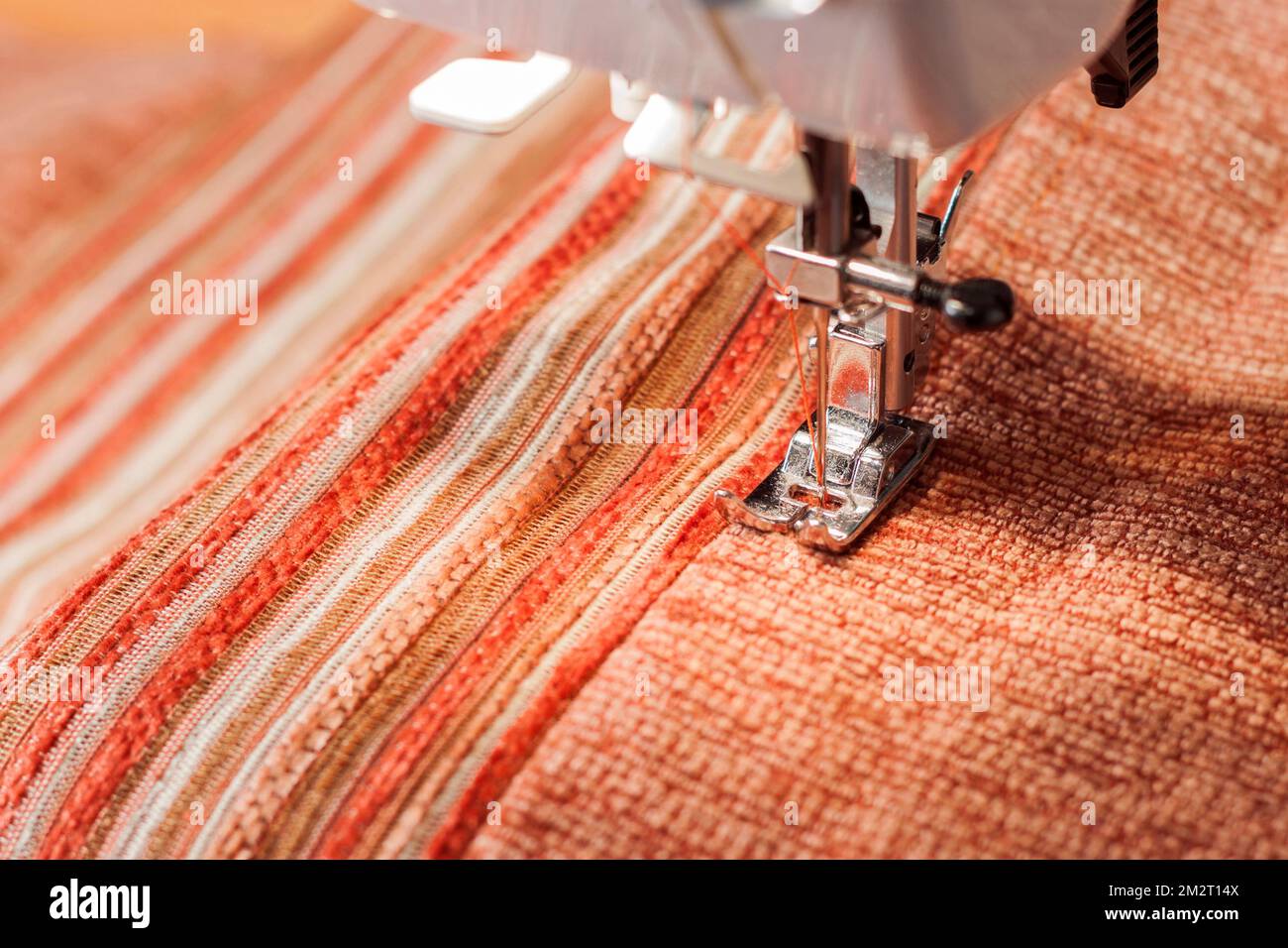Machine à coudre presse le pied et le tissu orange. Processus de couture Banque D'Images