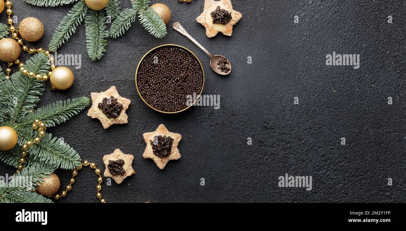 Caviar noir hors-d'œuvre étoiles sur une table noire décorée de noël bannière horizontale avec copyspace Banque D'Images