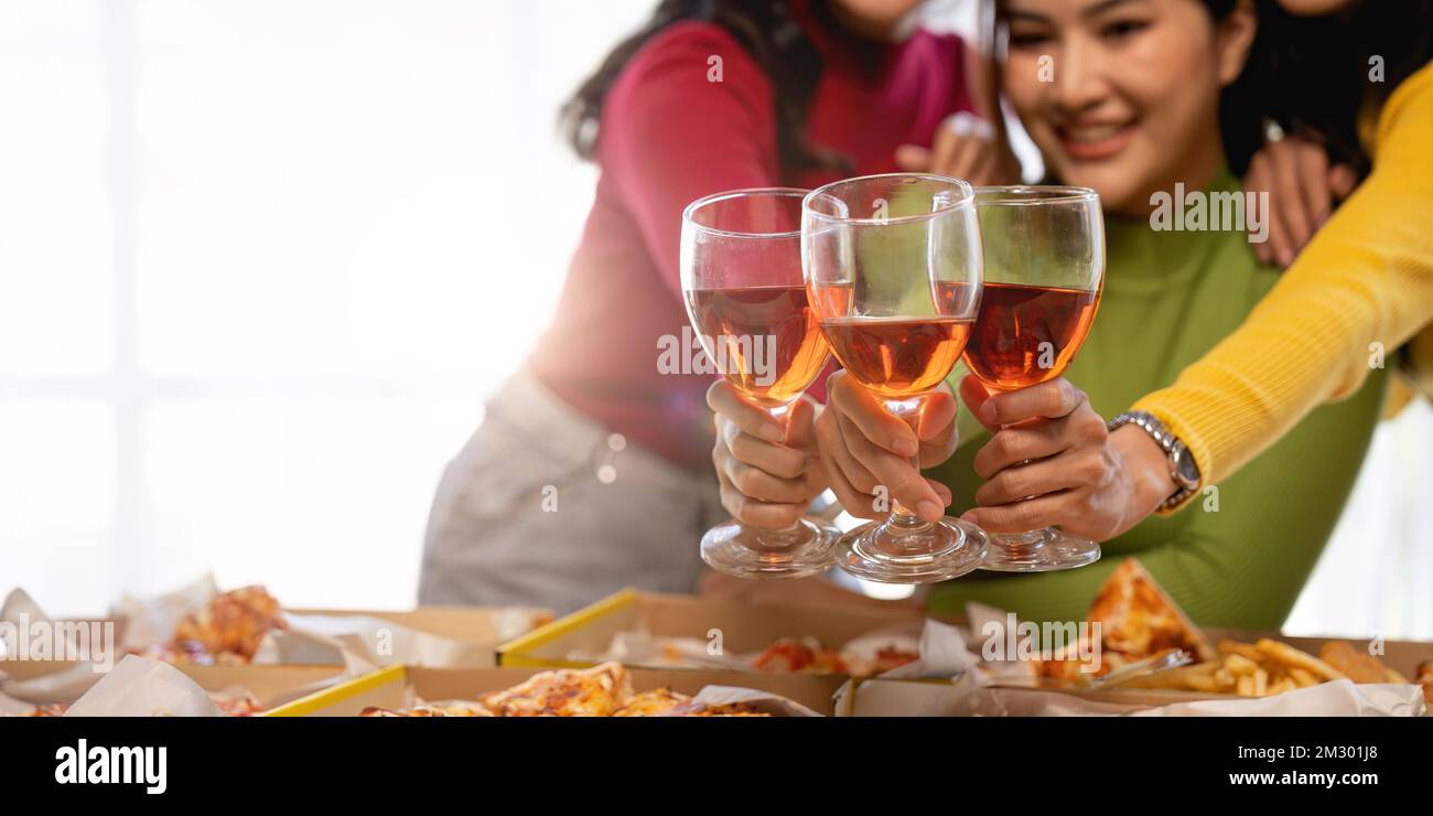 Un groupe d'amis asiatiques se réunit pour célébrer Noël avec du champagne et des pizzas à la maison. La joie des fêtes avec des amis ou un collègue concept Banque D'Images