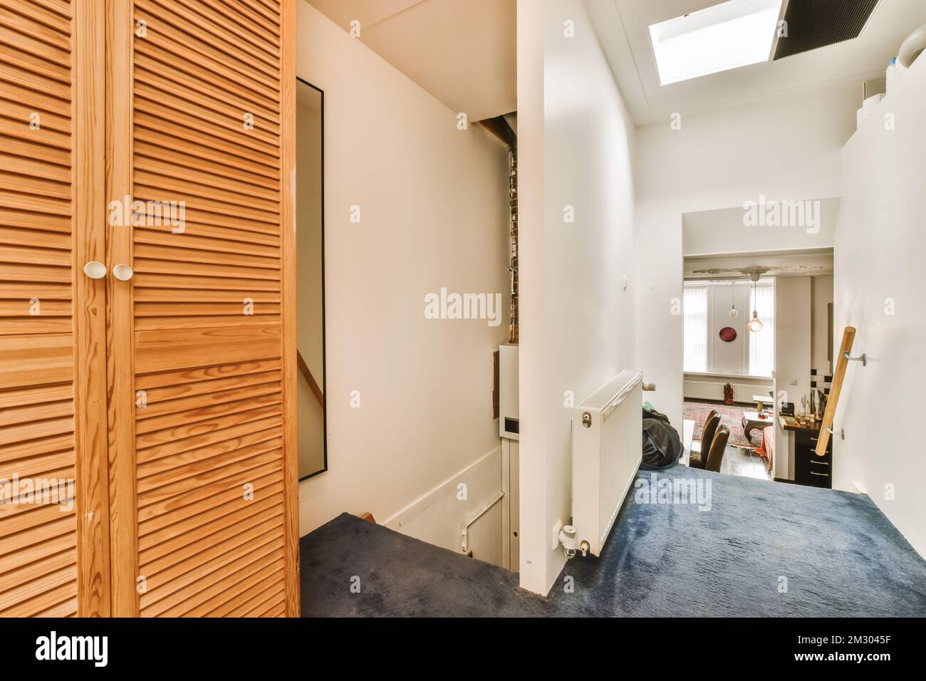 un couloir avec des volets en bois sur le mur et de la moquette bleue devant la porte de la chambre est blanc Banque D'Images