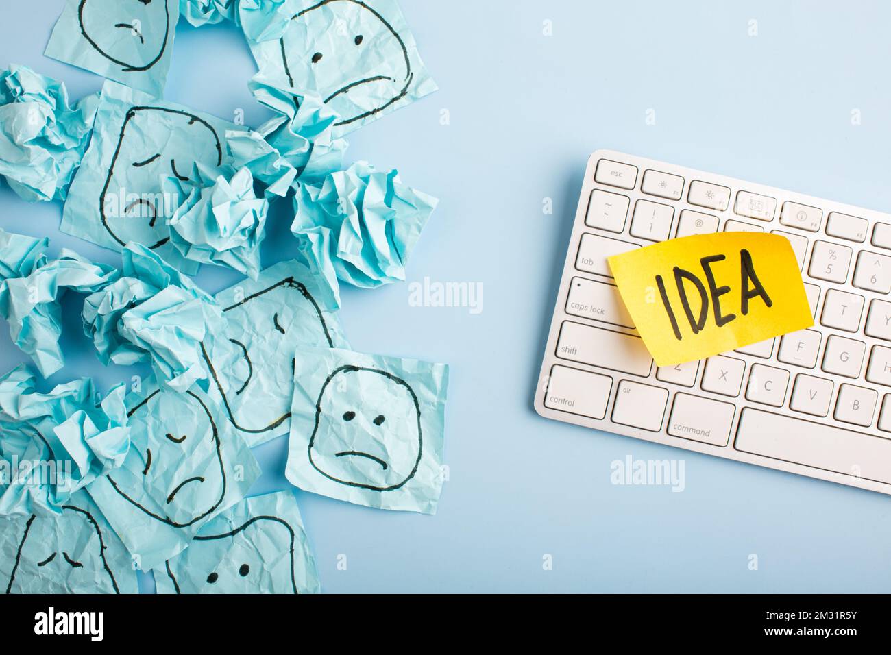 Un triste visage regardant des visages souriants de loin. Visages heureux et tristes dessinés sur des autocollants bleus. Concepts d'exclusion, de différence, de jalousie. Pho de haute qualité Banque D'Images