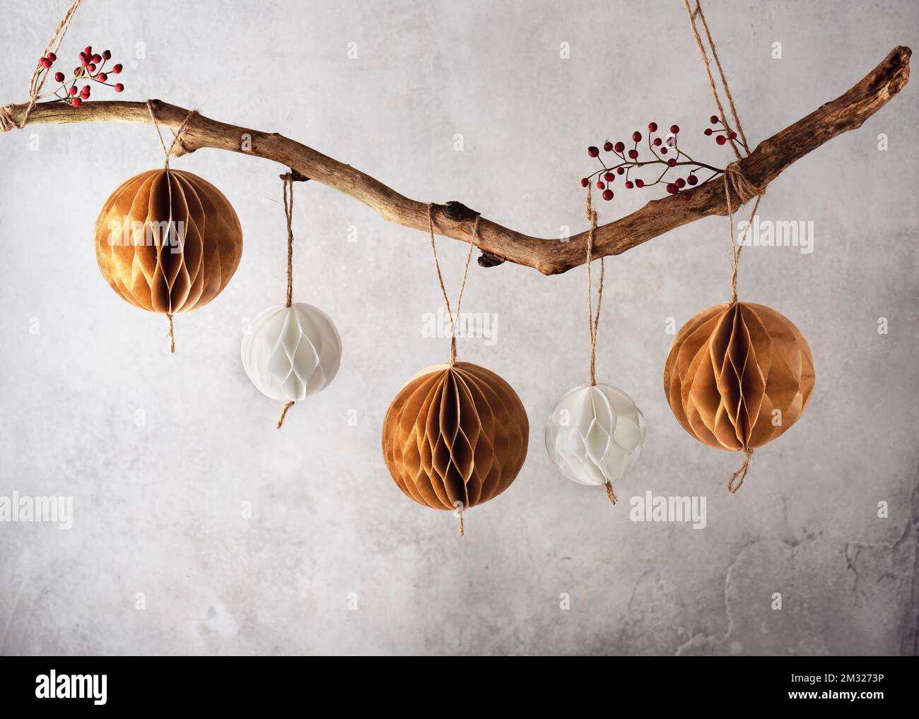 Balles en papier nid d'abeille faites à la main accrochées à la branche d'un arbre. Belle décoration de Noël pour la maison. Concept de papier scandinave artisanal nordique. Banque D'Images
