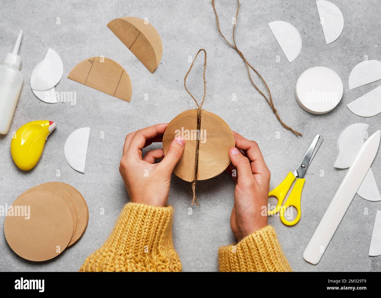 Étape 7. Plier le cercle au centre des deux côtés. Faire des balles de nid d'abeille à partir de papier filtre caffe pour Noël avec les enfants. Banque D'Images