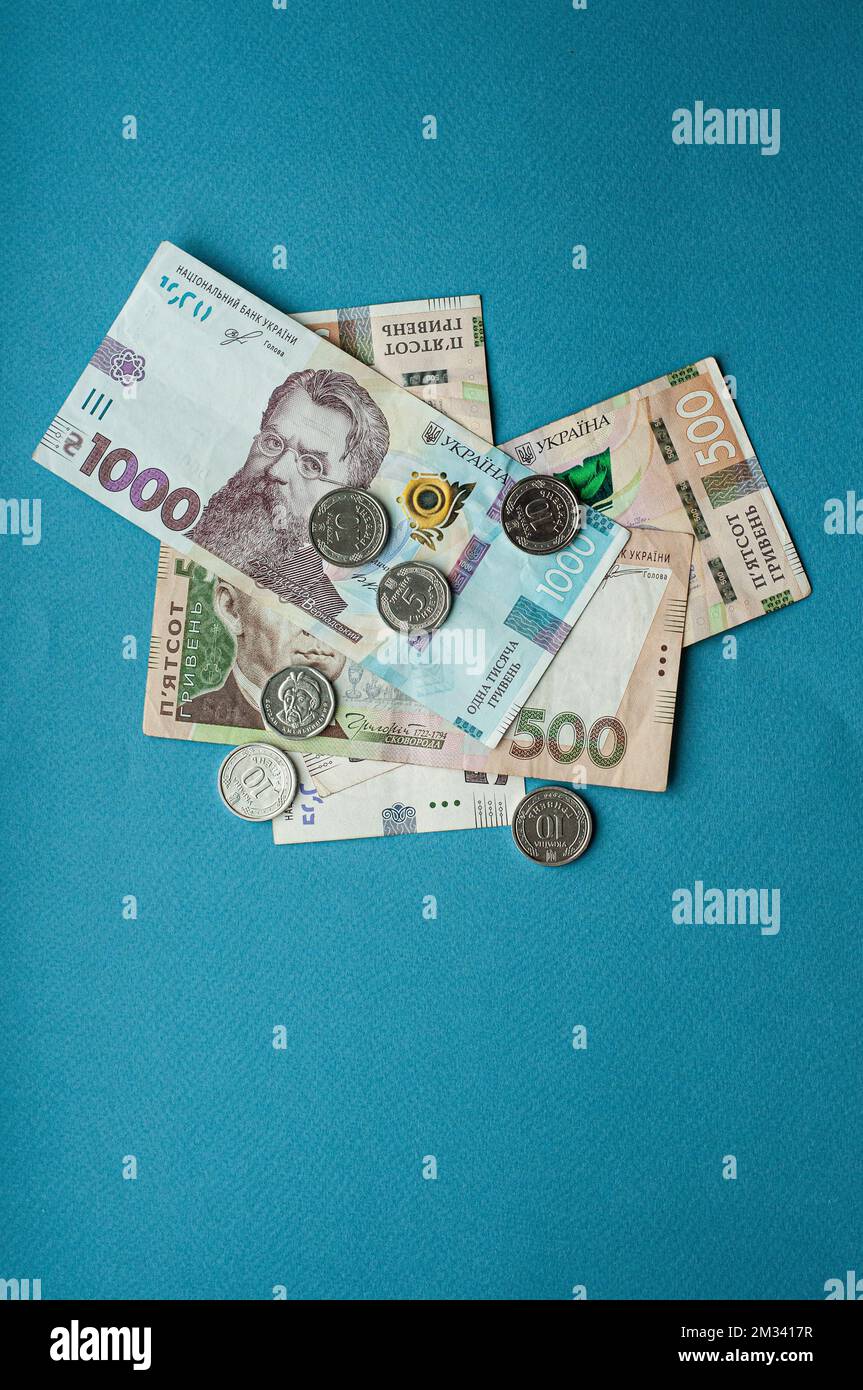 Argent comptant monnaie ukrainienne hryvnia cinq cents hryvnia mille billets et pièces monnaie revenus concept dollars sur un fond bleu Banque D'Images