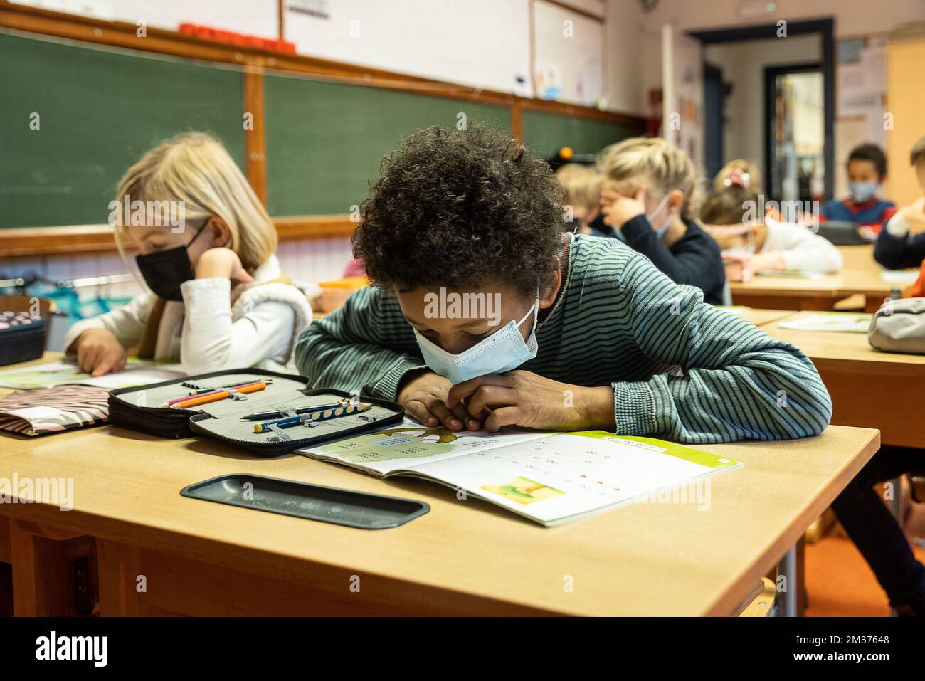 L'illustration montre des écoliers qui portent des masques buccaux dans leur salle de classe dans une école primaire de Gand, lundi 06 décembre 2021. À partir d'aujourd'hui, les enfants de six ans doivent porter une casquette dans les espaces publics, y compris dans les écoles. L'obligation de masque buccal s'inscrit dans le cadre de nouvelles mesures de sécurité et d'assainissement renforcées dans le contexte de la pandémie continue de Covid-19. BELGA PHOTO JAMES ARTHUR GEKIERE Banque D'Images