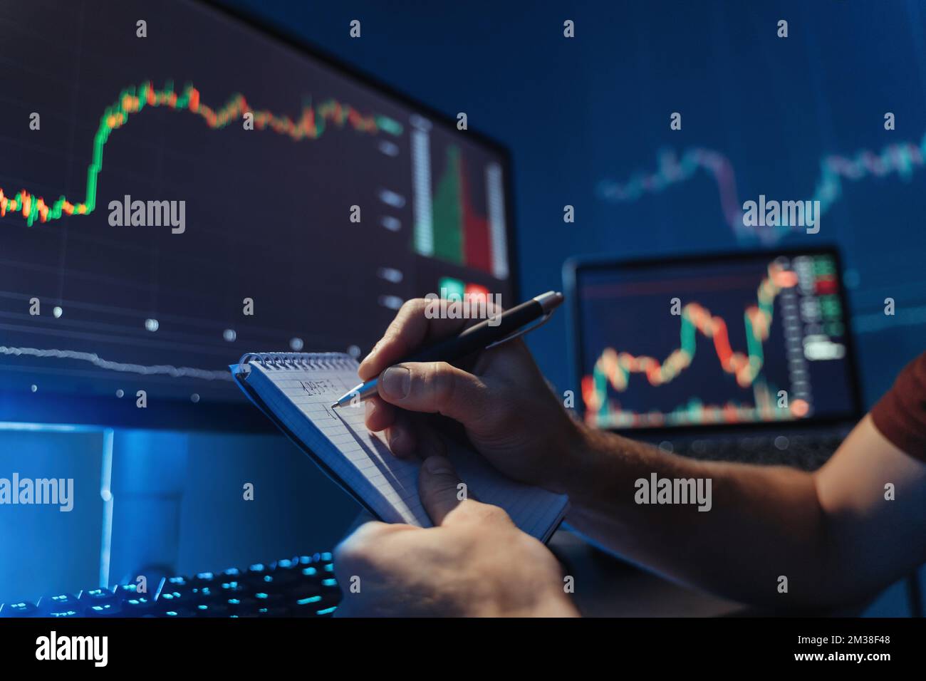 Aucune image faciale des mains masculines écrivant des chiffres dans le bloc-notes après avoir analysé le schéma du marché de la crypto-monnaie sur son pc, prédire les modèles de flux d'argent, inventer une nouvelle stratégie évitant les risques élevés Banque D'Images