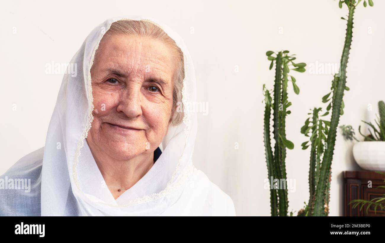 Portrait d'une vieille femme musulmane des années 80 portant le hijab blanc assis à la maison pendant le jeûne pendant le mois du Ramadan. Banque D'Images