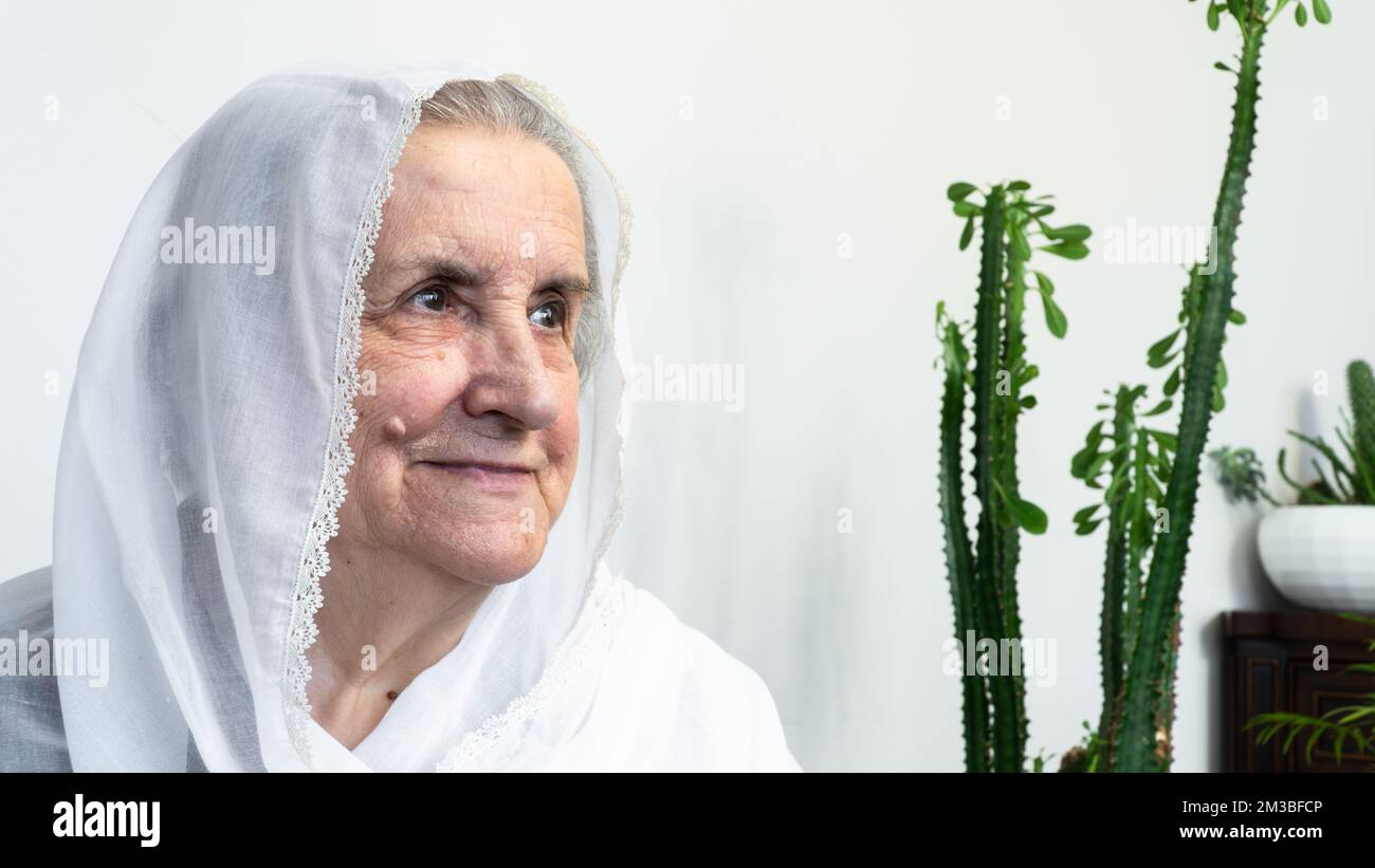 Portrait d'une vieille femme musulmane des années 80 portant le hijab blanc assis à la maison pendant le jeûne pendant le mois du Ramadan. Banque D'Images
