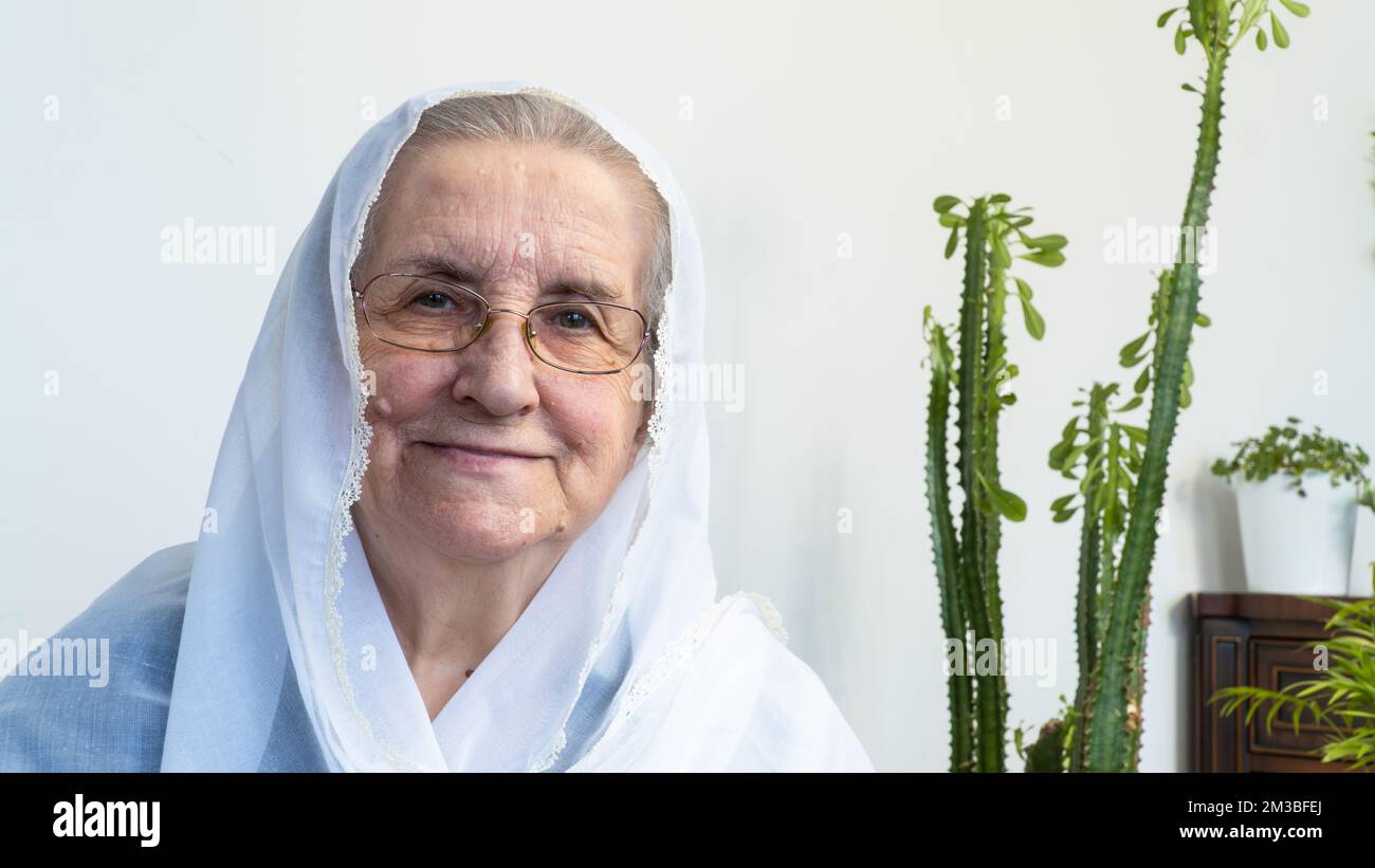 Portrait d'une vieille femme musulmane des années 80 portant le hijab blanc assis à la maison pendant le jeûne pendant le mois du Ramadan. Banque D'Images