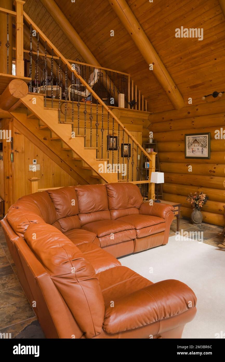 Salon et escalier menant à la chambre principale à l'étage à l'intérieur d'une maison en rondins résidentielle. Banque D'Images