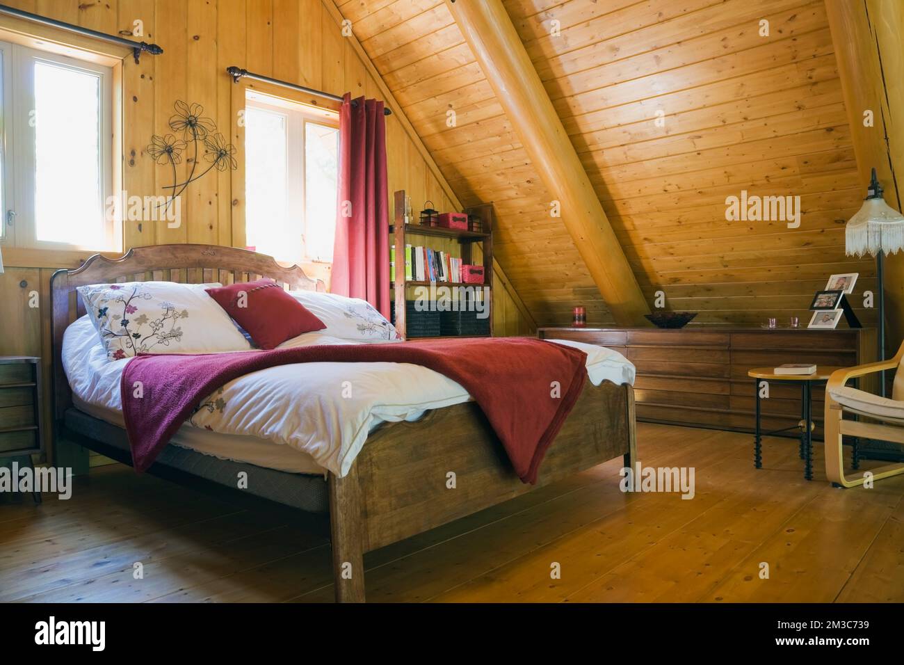 Lit double à cadre en bois avec couvre-lit blanc et couverture rouge dans  la chambre principale à l'étage à l'intérieur de la cabane en rondins Photo  Stock - Alamy