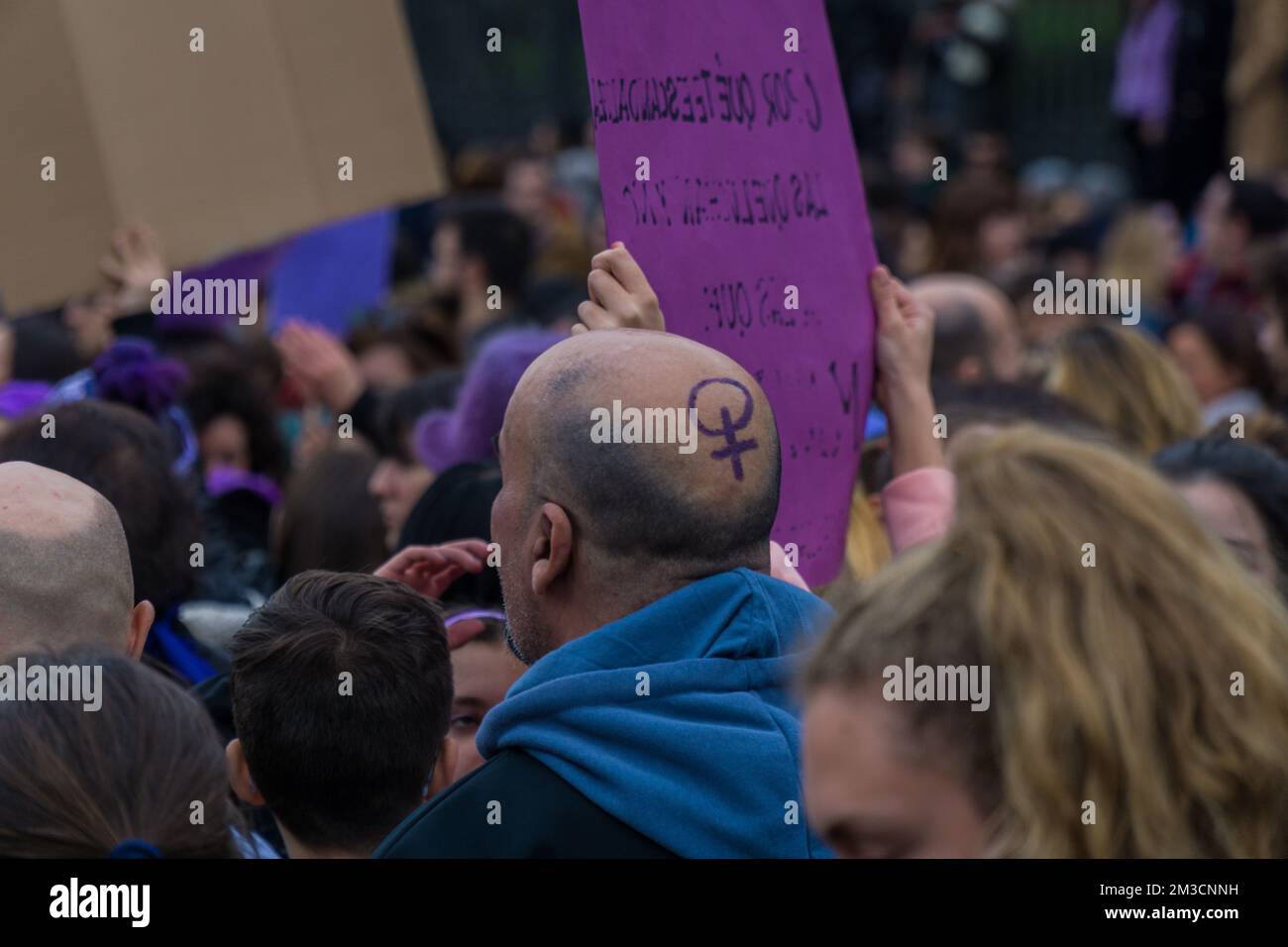 Un homme chauve au symbole féminin violet peint dans sa tête pendant 8M marches de la Journée internationale de la femme en revendiquant ses droits Banque D'Images