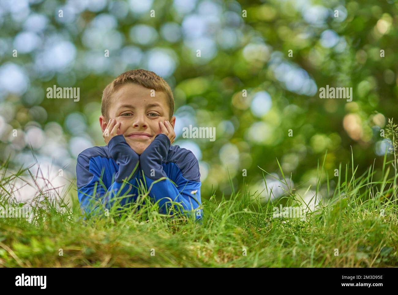 Un portrait d'un jeune garçon heureux dans un parc vert, en pensée profonde. Banque D'Images