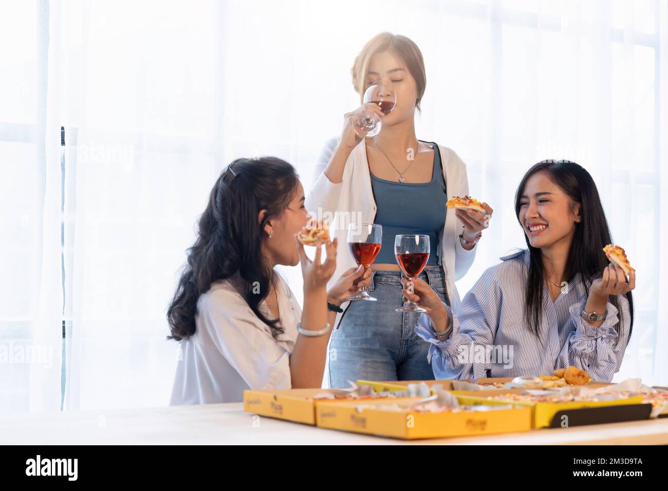 Un groupe d'amis asiatiques se réunit pour célébrer Noël avec du champagne et des pizzas à la maison. La joie des fêtes avec des amis ou un collègue concept Banque D'Images