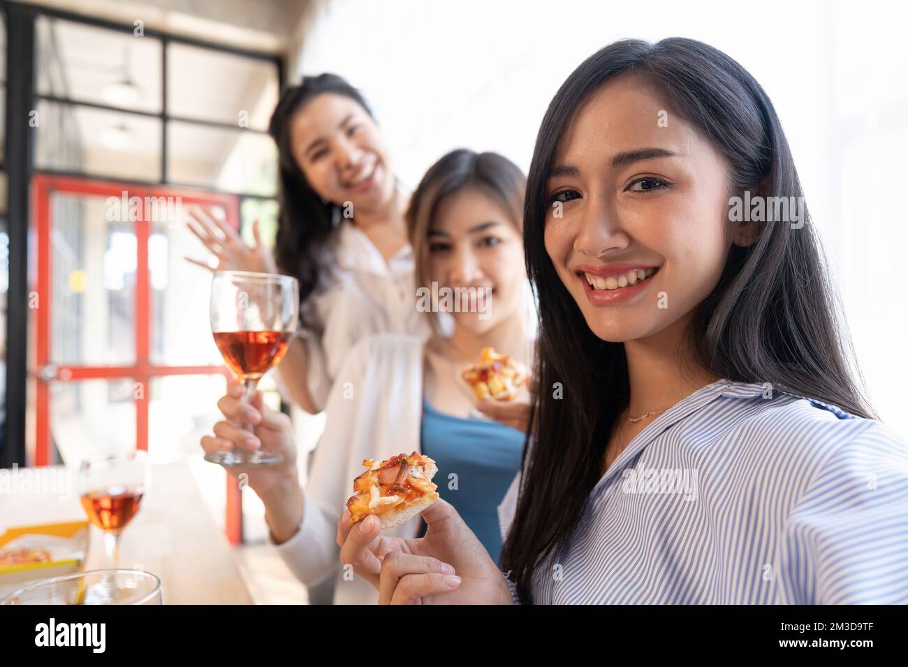 Un groupe d'amis asiatiques se réunit pour célébrer Noël avec du champagne et des pizzas à la maison. La joie des fêtes avec des amis ou un collègue concept Banque D'Images