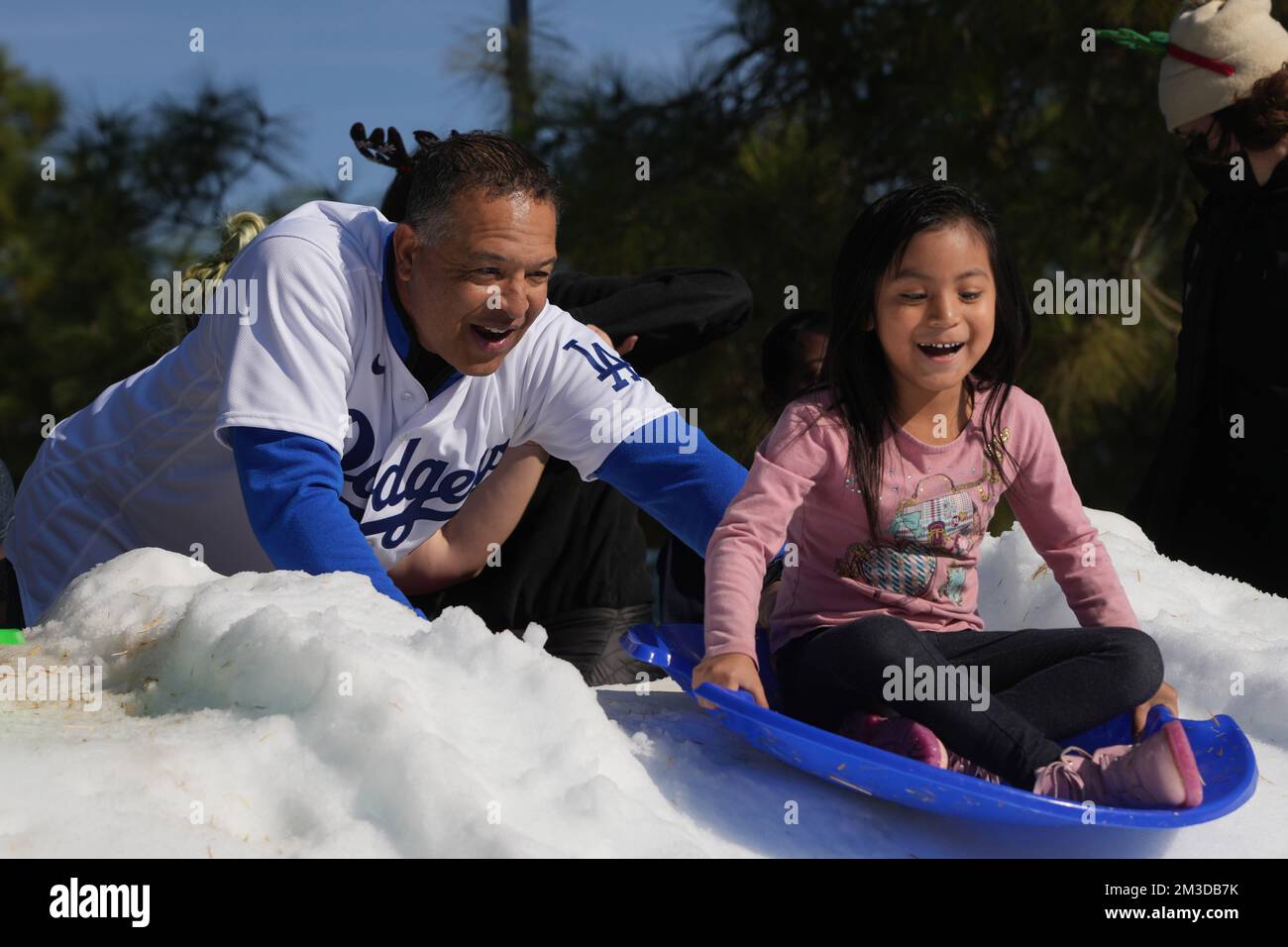 Le manager des Dodgers de Los Angeles, Dave Roberts, assiste les étudiants sur une colline de traîneau à neige lors de la fête des Fêtes de la Dodgers Foundation, le mercredi 14 décembre 2022, à Los Angeles. Banque D'Images