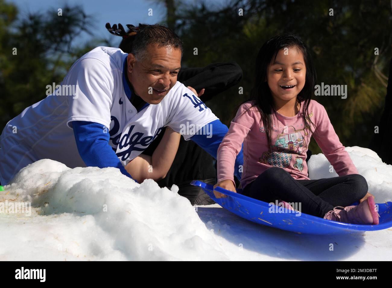 Le manager des Dodgers de Los Angeles, Dave Roberts, assiste les étudiants sur une colline de traîneau à neige lors de la fête des Fêtes de la Dodgers Foundation, le mercredi 14 décembre 2022, à Los Angeles. Banque D'Images