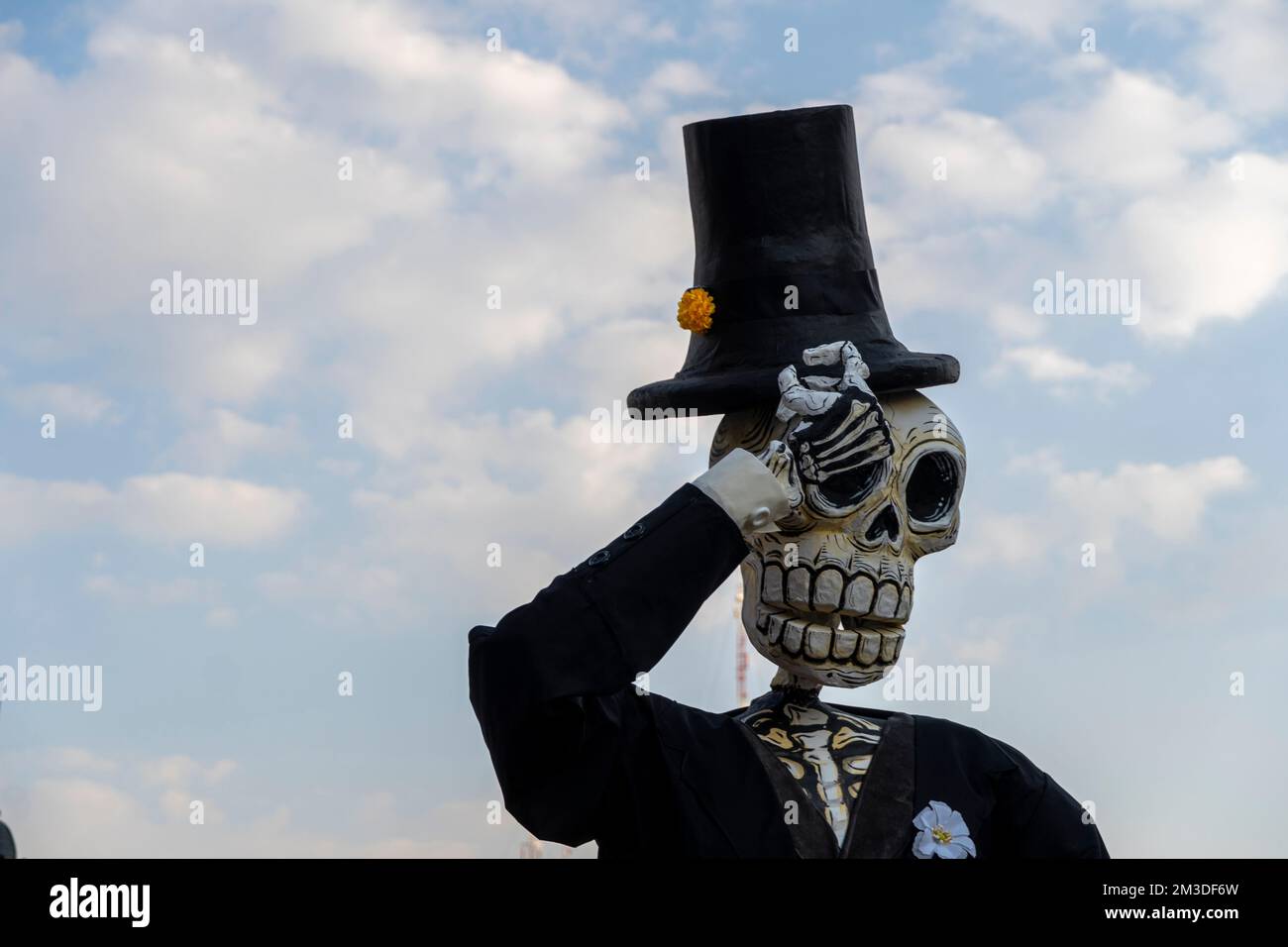 crânes de papier géantes vêtues de costume noir dans le ciel bleu d'arrière-plan avec des nuages Banque D'Images