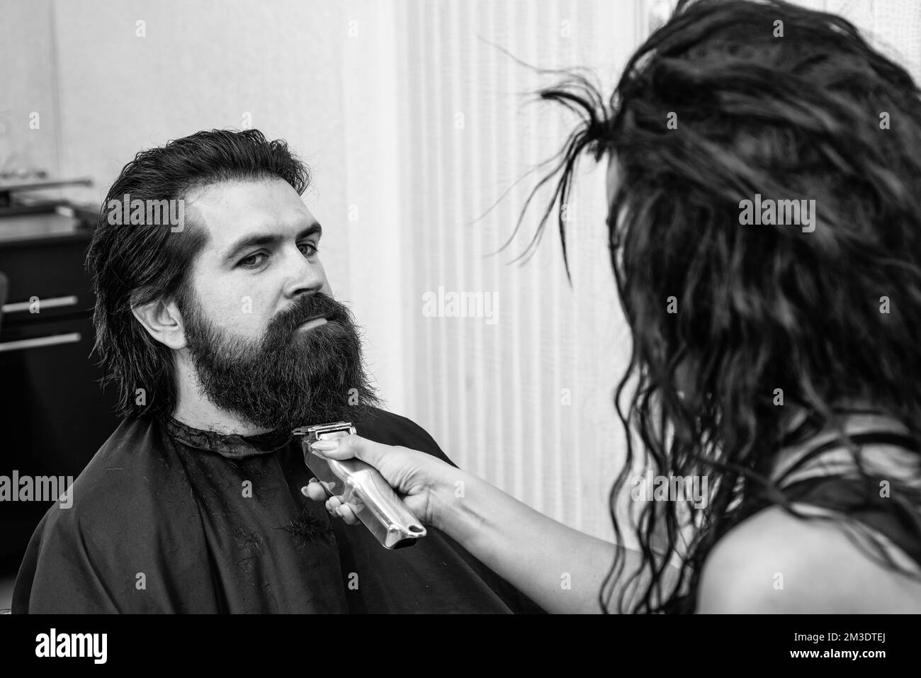 un boxeur mûr avec barbe et moustache se charge de ses cheveux dans un salon de coiffure, le toilettage de la barbe Banque D'Images