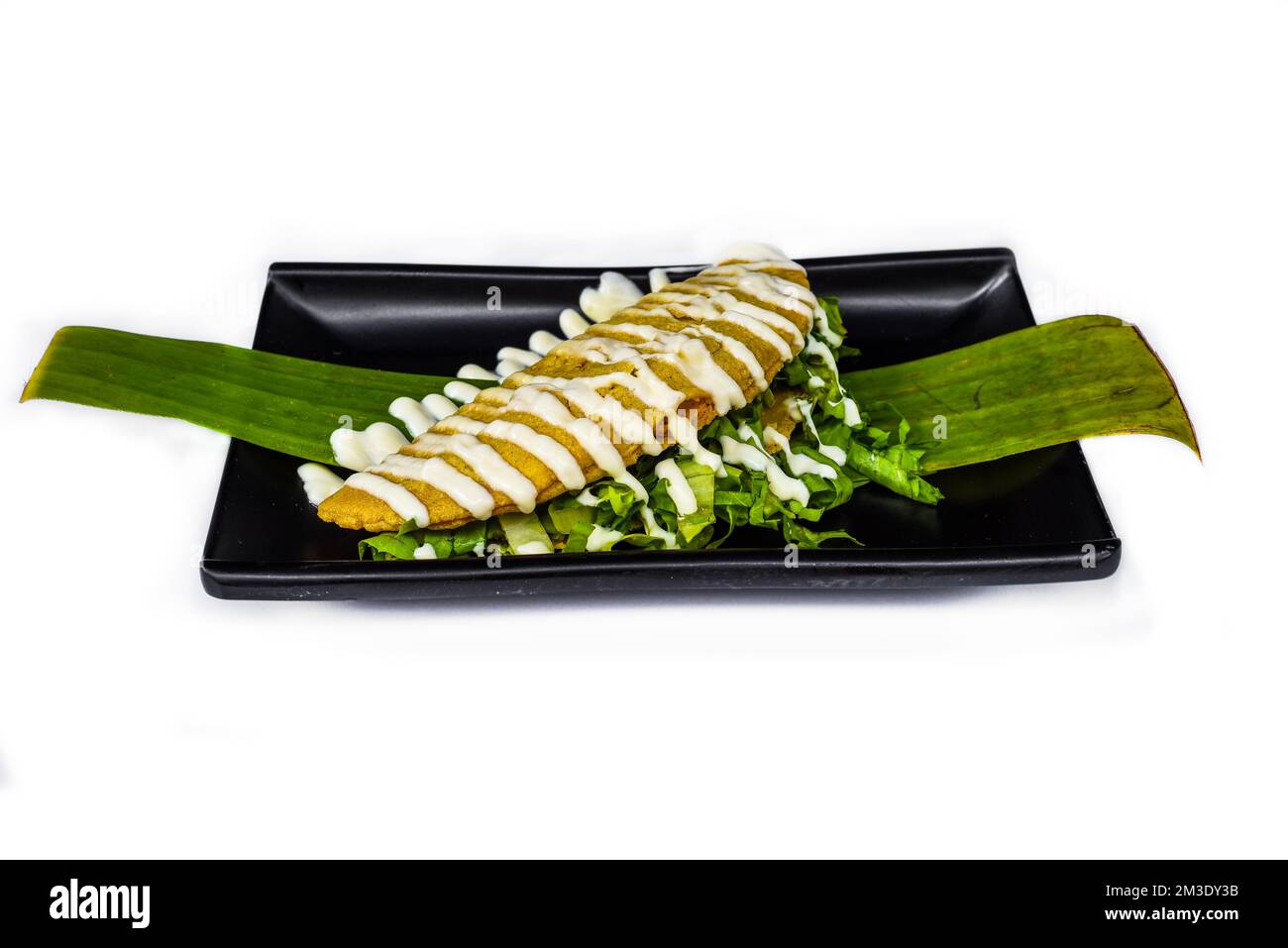 Taco xochimilco ami avec la pâte de masa laitue et la crème sure sur plaque noire isolée sur fond blanc Banque D'Images