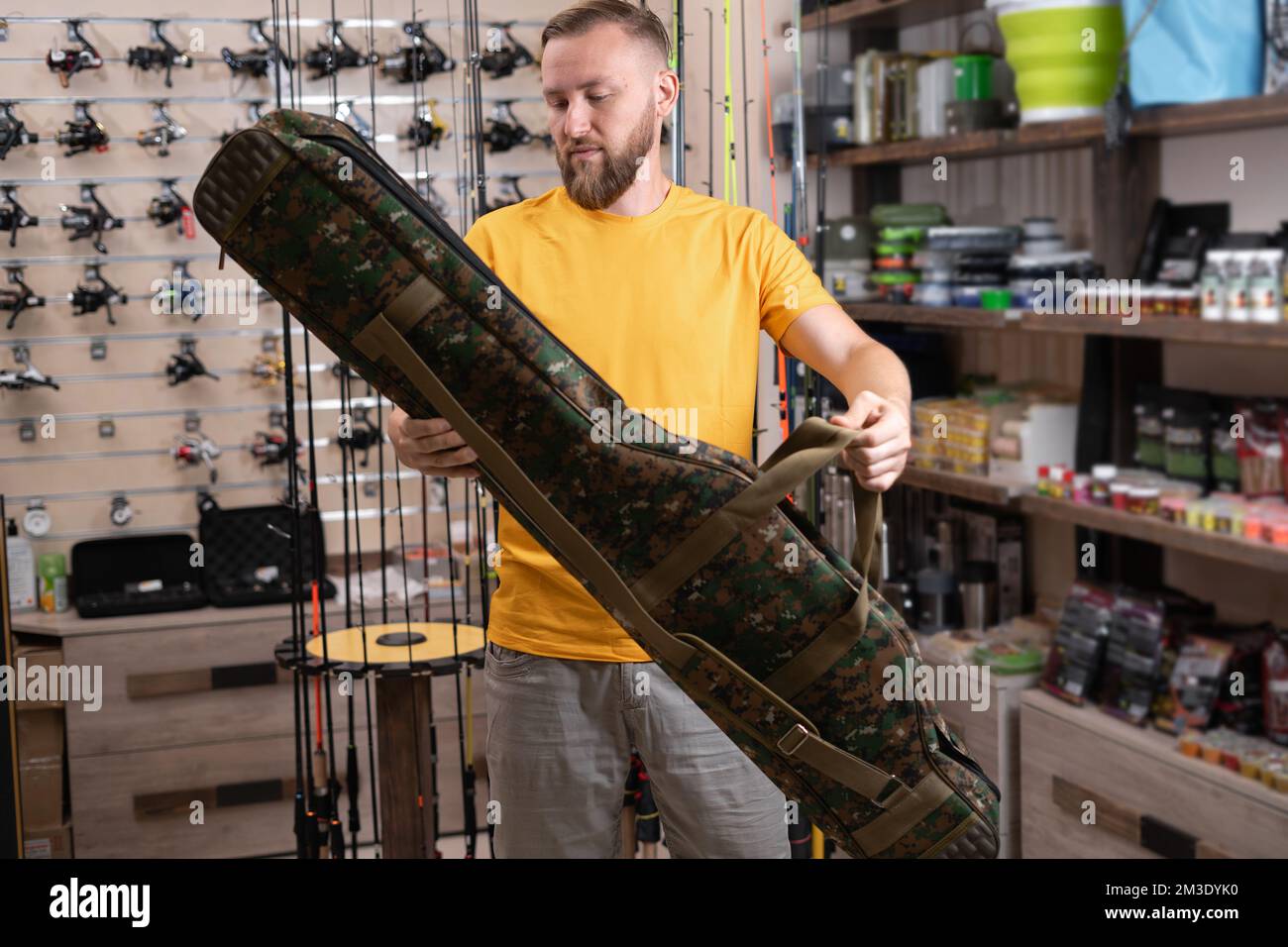 Un homme qui choisit un étui pour canne à pêche dans une boutique de sport. copier l'espace Banque D'Images