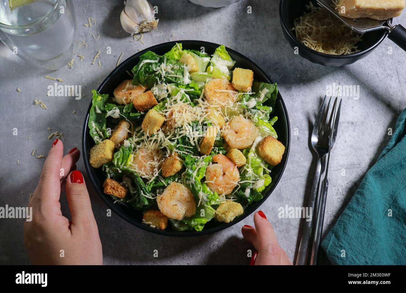 Gros plan de la femme mangeant de la salade César à la fourchette sur une table en marbre gris Banque D'Images