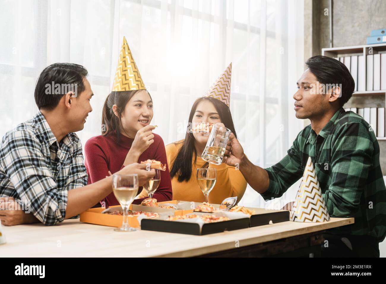 Un groupe d'amis asiatiques se réunit pour célébrer Noël avec du champagne et des pizzas à la maison. La joie des fêtes avec des amis ou des collègues Banque D'Images